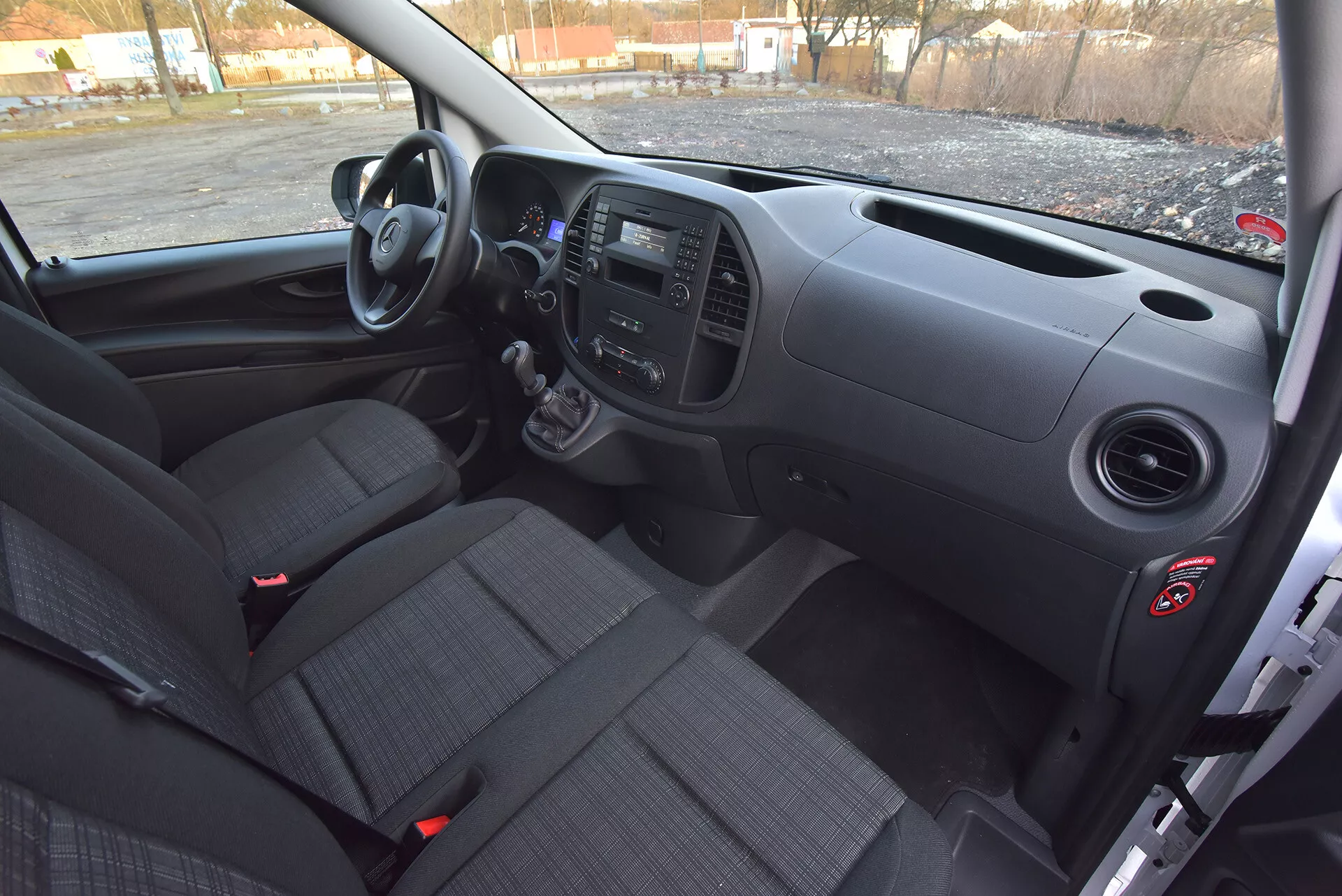 Visão interior do Mercedes-Benz Vito Tourer de 2014 pelo lado do motorista mostrando o painel frontal, transmissão manual, painéis de controle e assentos de tecido