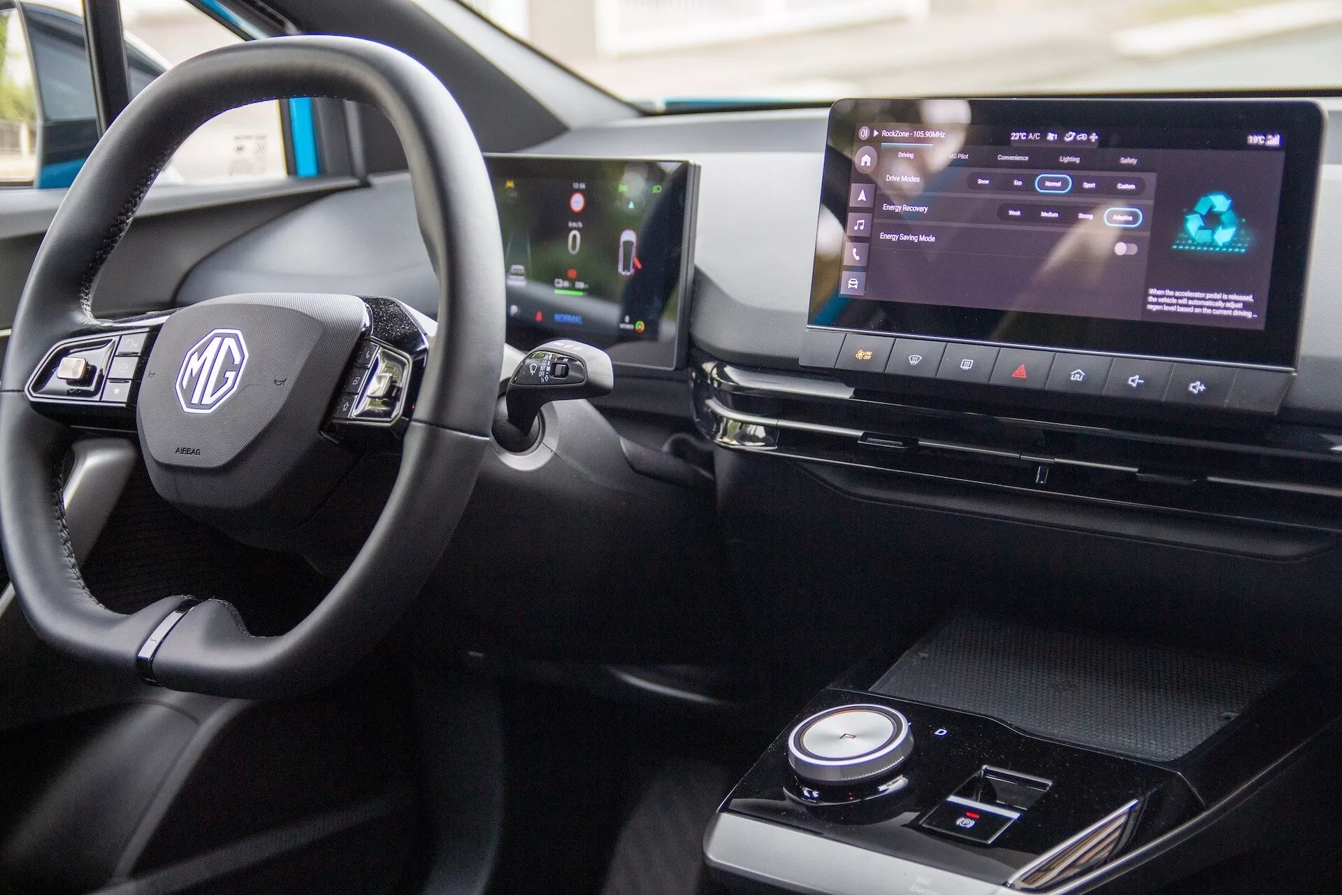 Visão aproximada do interior do MG MG4 2022, com volante com controles, painel de instrumentos digital e sistema de infotainment widescreen em configuração de condução à direita