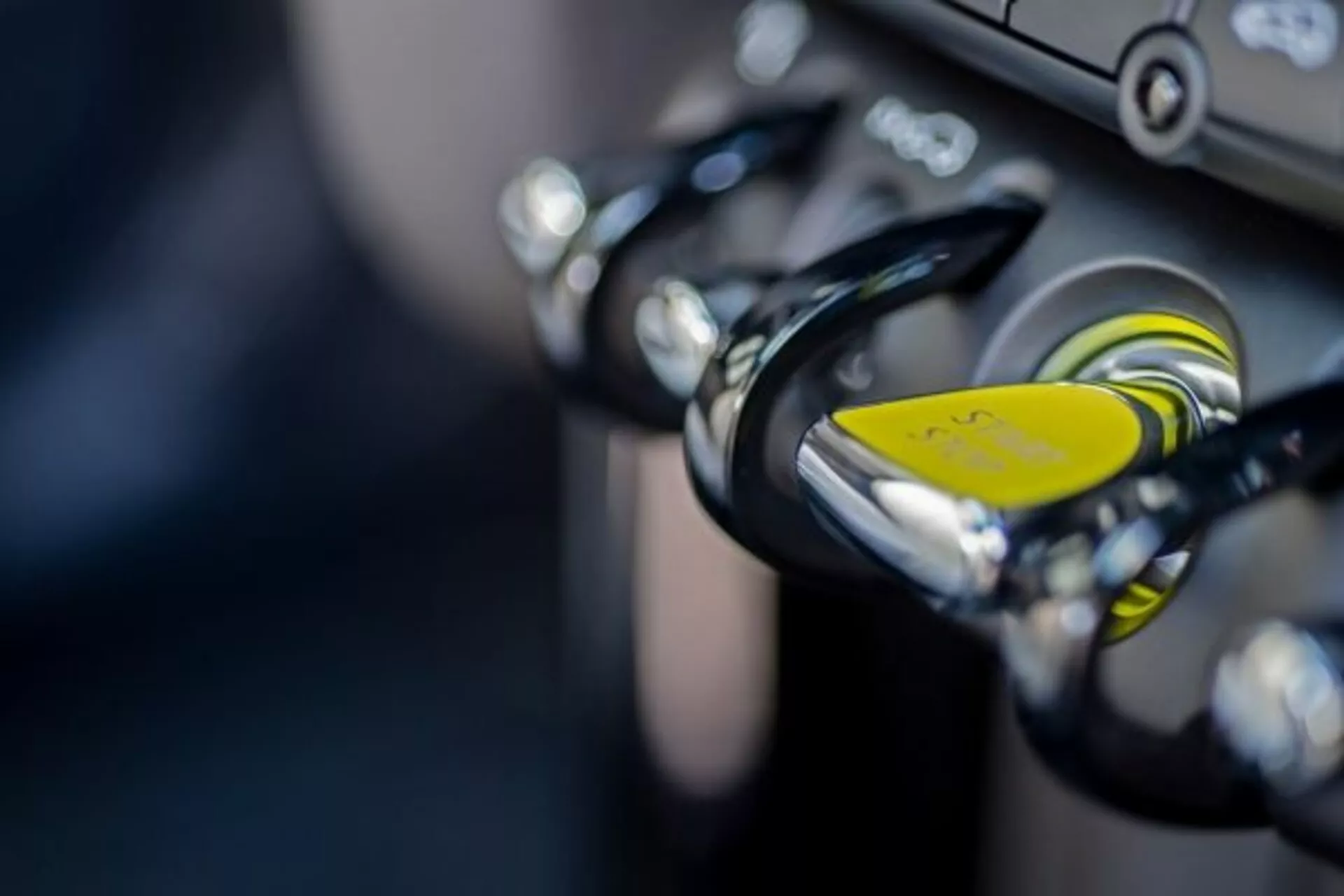 Close-up da ignição de uma moto com entrada de chave e chaveiro amarelo, exibindo tecnologia antifurto e guidões com detalhes em cromo, ilustrando características de design de alta qualidade e recursos de segurança.