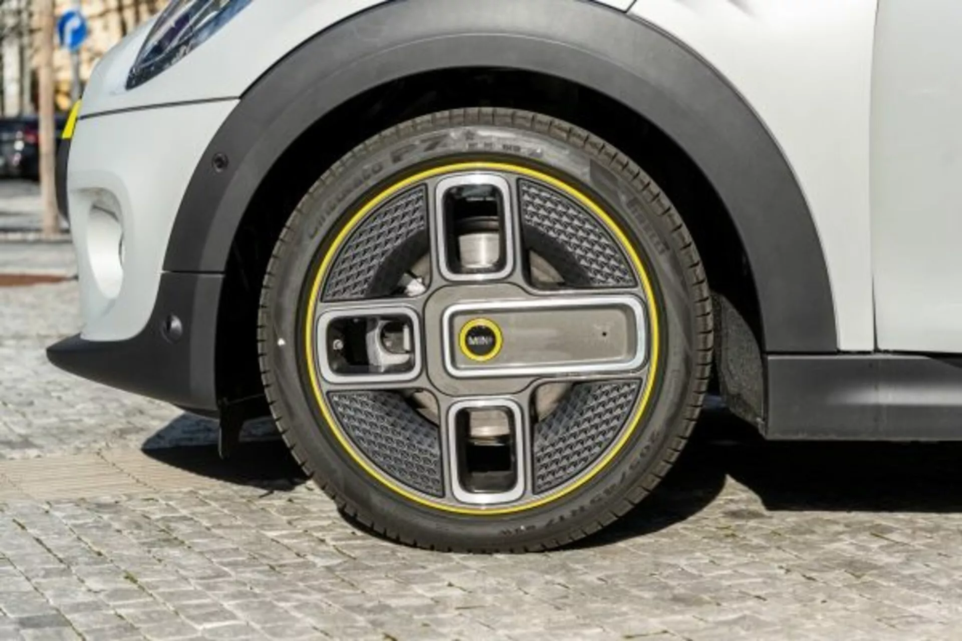 Visão detalhada da roda frontal do Mini Mini de 3 portas de 2018 com design futurista em dois tons e tampa de cubo integrada, indicando inovação em veículos elétricos e aerodinâmica avançada, contra um corpo de carro branco