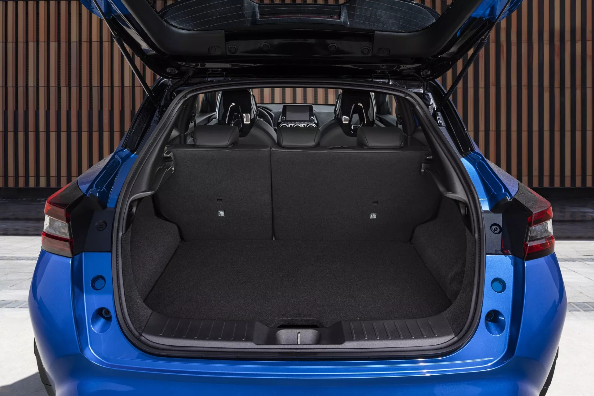 Vista traseira de um Nissan Juke azul de 2019 F16 com a bagageira aberta mostrando o espaço de carga e as características de design à luz do dia