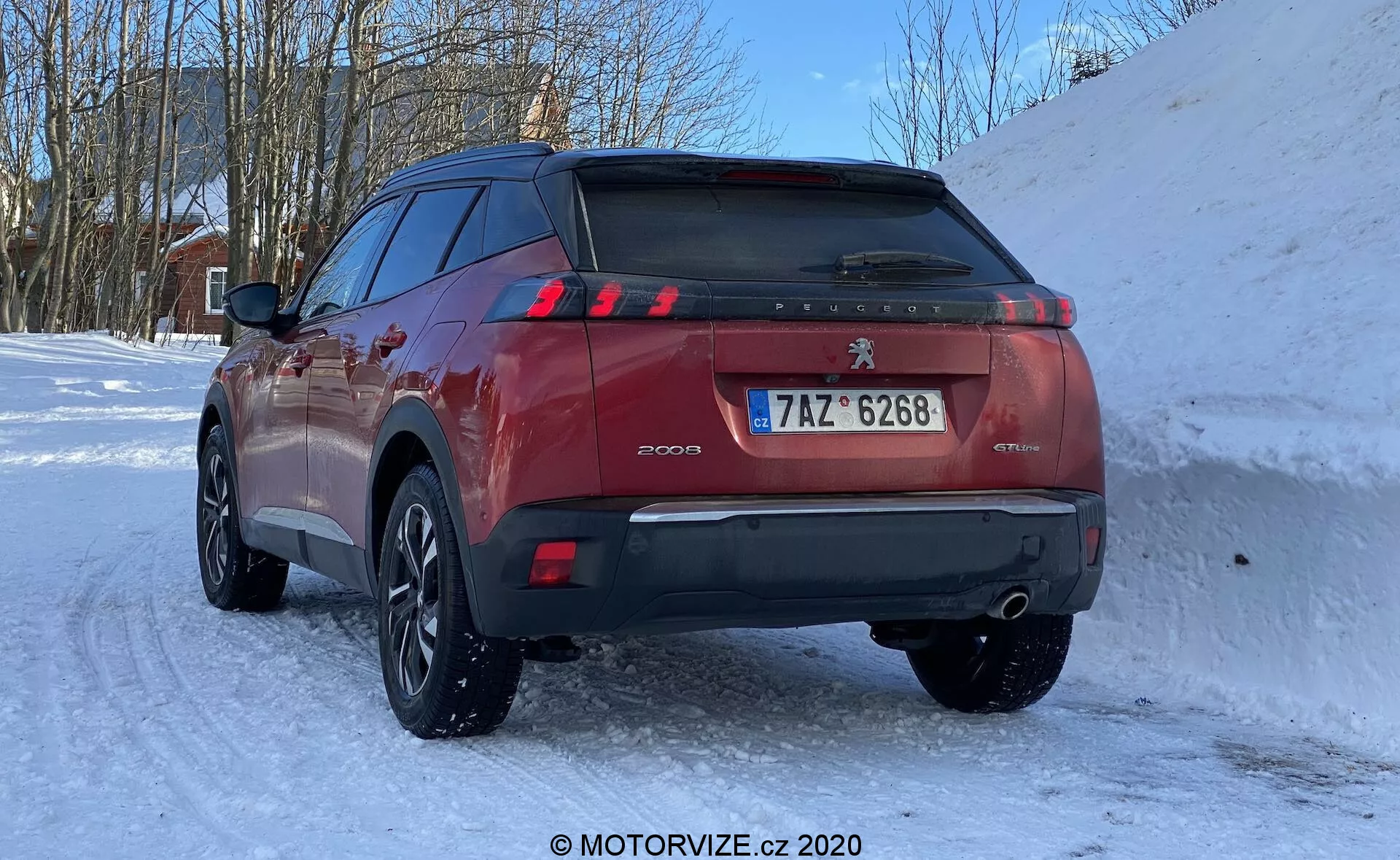Peugeot 2008 1.2 PureTech 100 Active SUV 2020 em um cenário de inverno nevado, visão traseira de três quartos destacando a porta traseira, luzes traseiras em LED em forma de garra, sensores de estacionamento no para-choque traseiro, duplo escapamento, placa de estilo europeu e rodas de liga leve com vários raios e pneus de inverno.