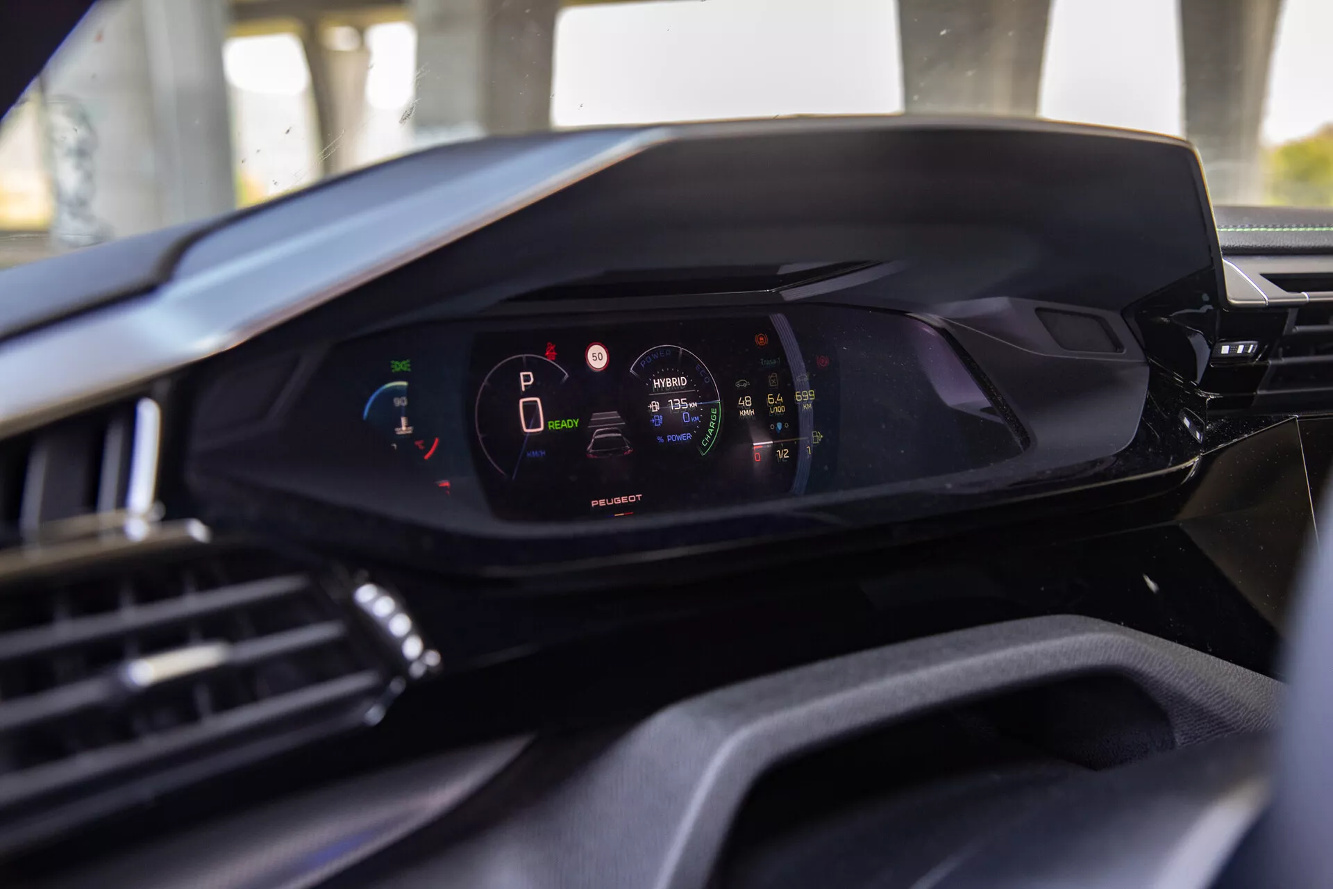 Vista interior do Peugeot 408 2023 destacando o painel digital moderno a partir da perspectiva do assento do motorista, realçando o cluster de instrumentos digital com o veículo em modo de estacionamento e alto nível de carga da bateria