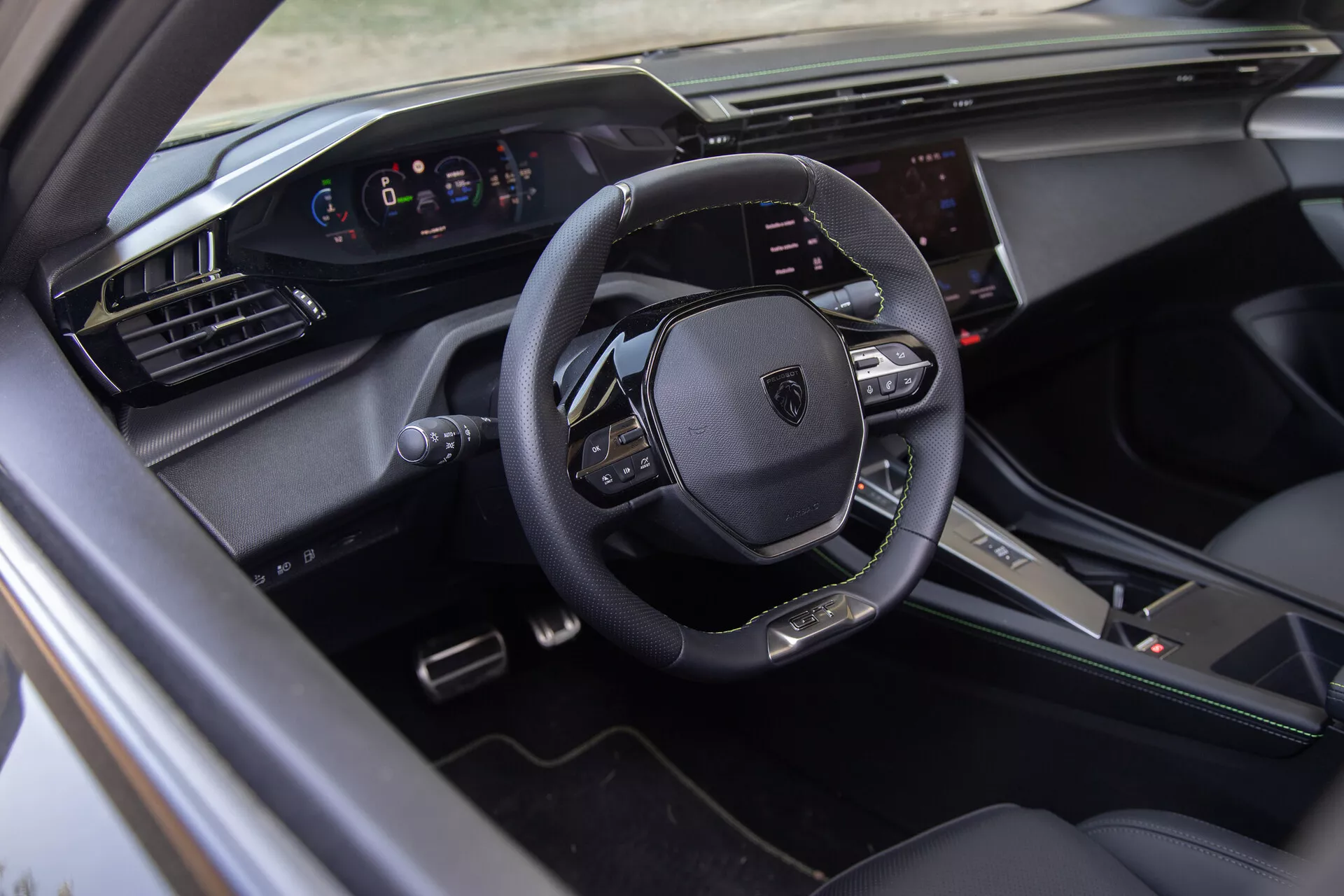 Interior do Peugeot 408 2023 mostrando um volante multifunções em couro, painel de instrumentos digital e sistema de infotainment touchscreen do ponto de vista do lado do motorista