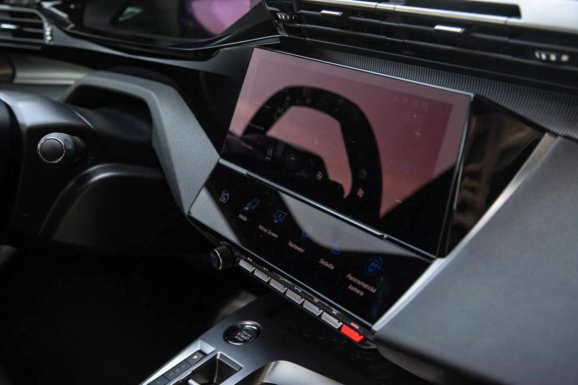 Interior do Peugeot 408 2023 mostrando o console central e o sistema avançado de infotainment com tela touchscreen, botões de controle de clima e elegantes acentos de design