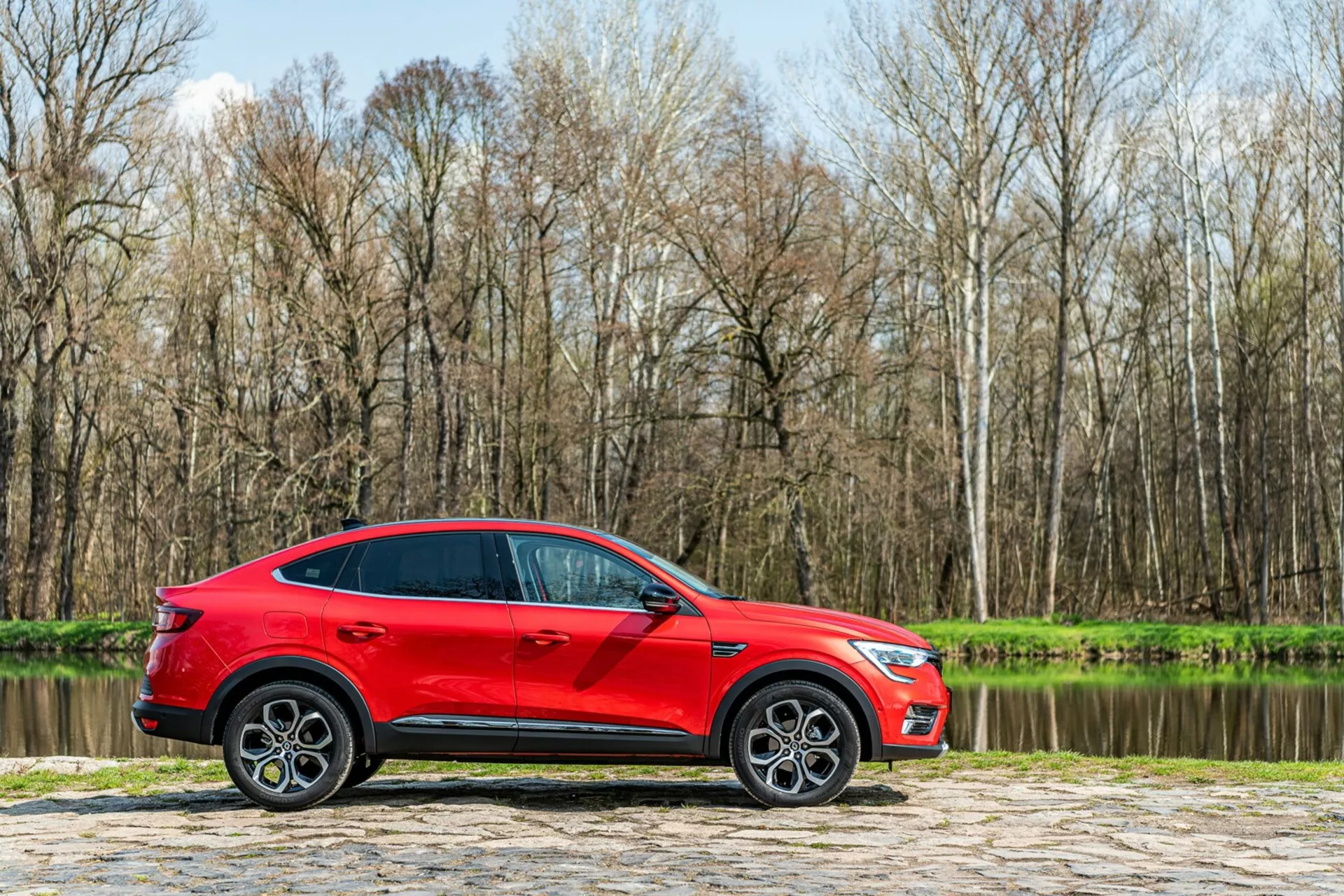 Vista frontal de um Renault Arkana 2021 com um design moderno e elegante, apresentando faróis LED elegantes e uma grade dinâmica e ousada, destacando seu apelo esportivo e sofisticado.