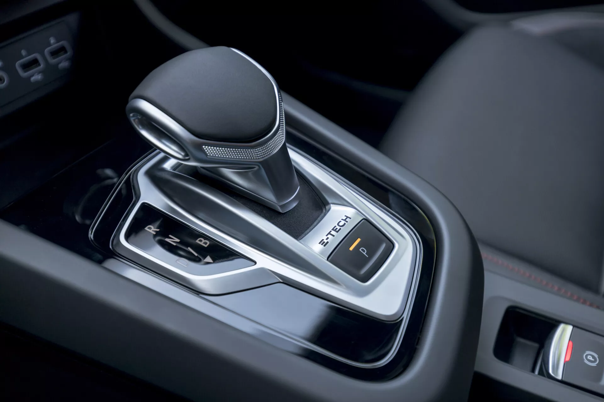 Vista aproximada da alavanca de mudanças de transmissão automática do Renault Arkana 2021 dentro do veículo, exibindo design moderno com botão revestido de couro, detalhes cromados e controle de freio de estacionamento eletrônico.