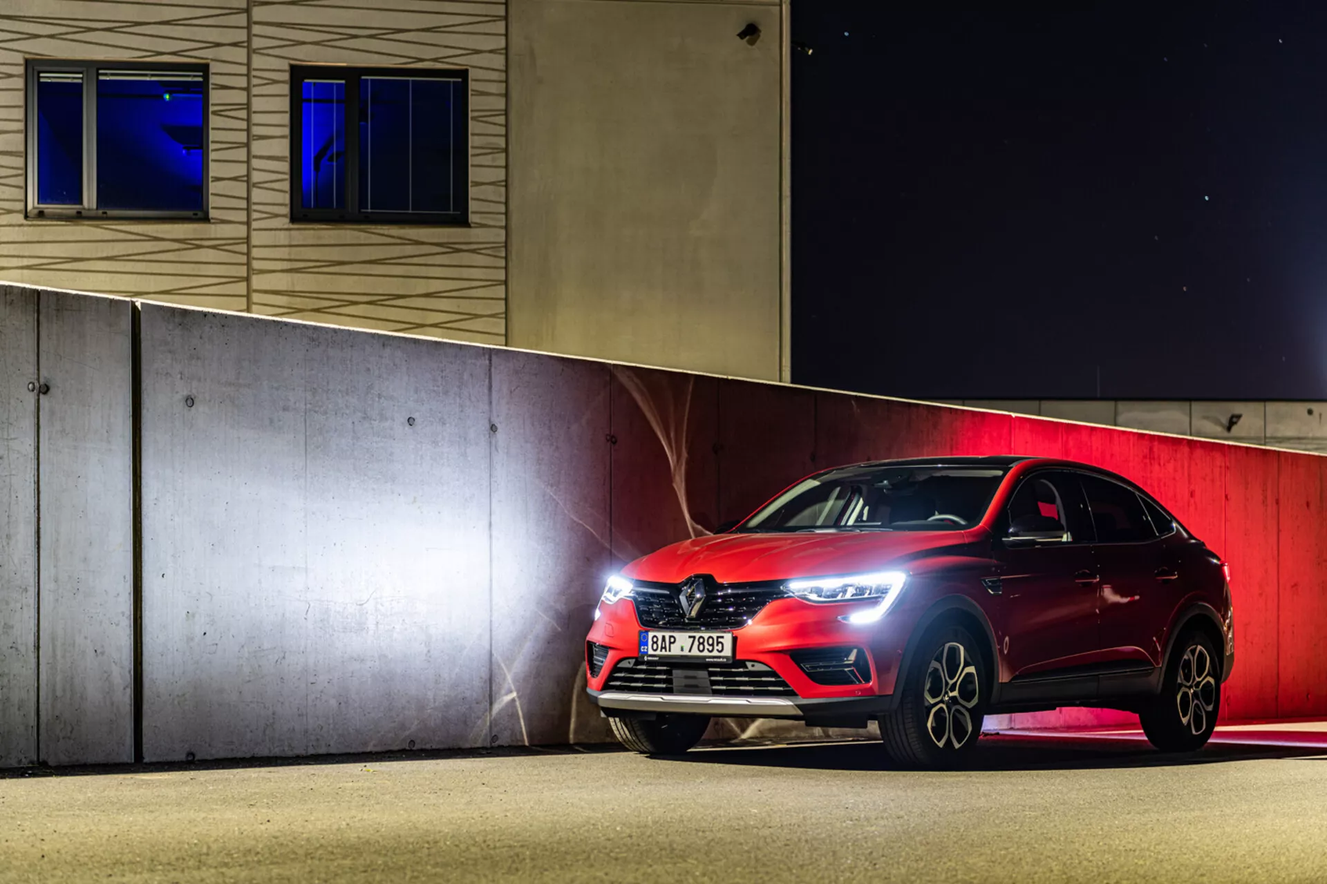 Hatchback esportivo Renault Arkana 2021 estacionado à noite, exibindo faróis LED, grade frontal e rodas de liga leve sob iluminação artificial