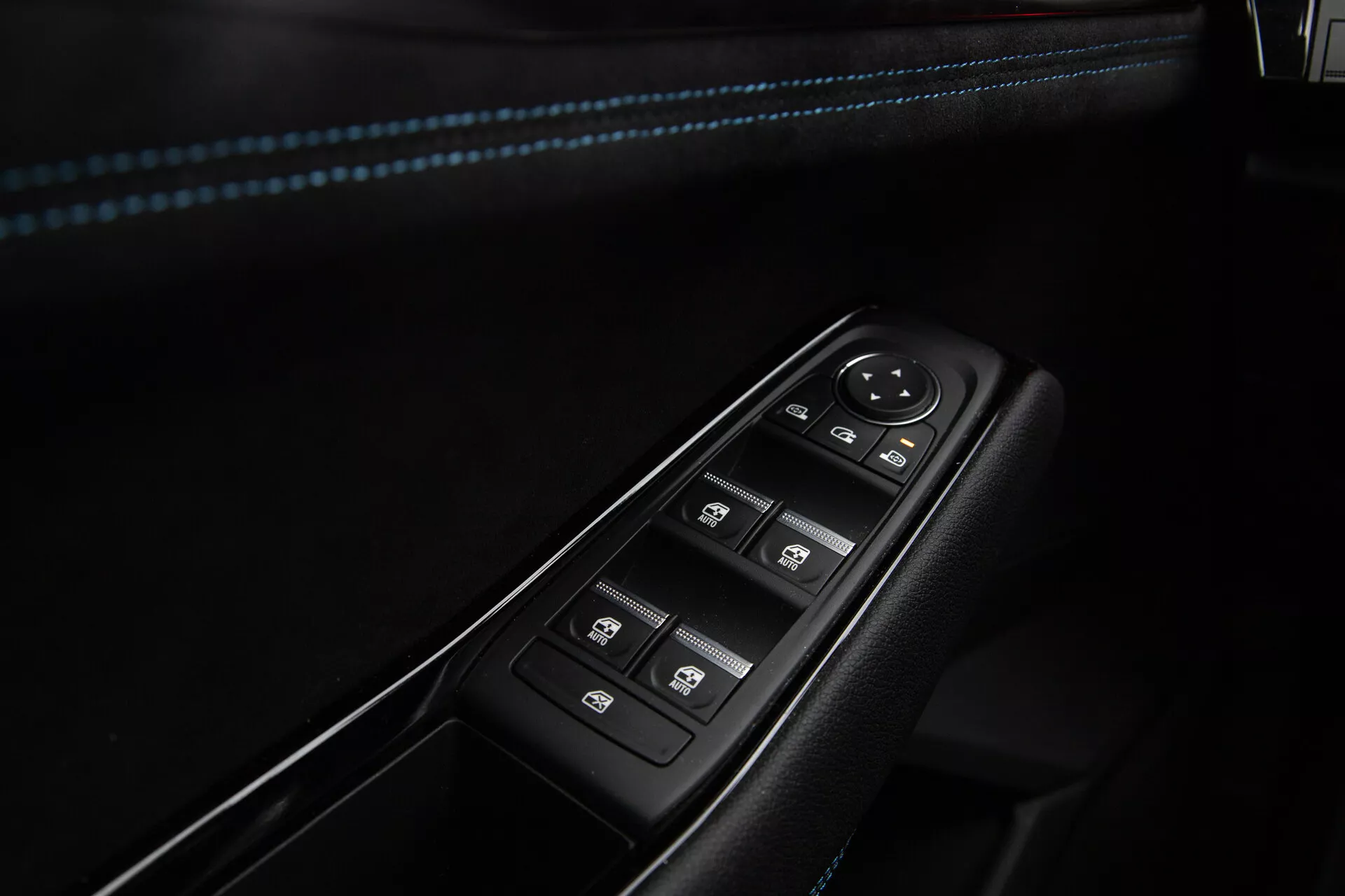 Visão aproximada dos controles de porta do lado do motorista do Renault Austral 2022, apresentando botões para o controlo de janelas elétricas com operação de um toque, manípulo de ajuste do espelho lateral eletrônico, e interruptor de bloqueio central, enquadrados num painel preto com acabamento em cromo e costura de realce azul no apoio de braço.