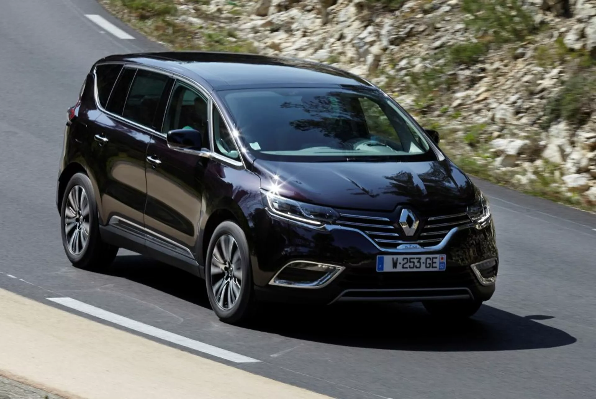 Minivan Renault Espace 2015 em movimento em estrada pavimentada, visão frontal de três quartos destacando faróis LED, rodas de liga leve e características de design moderno
