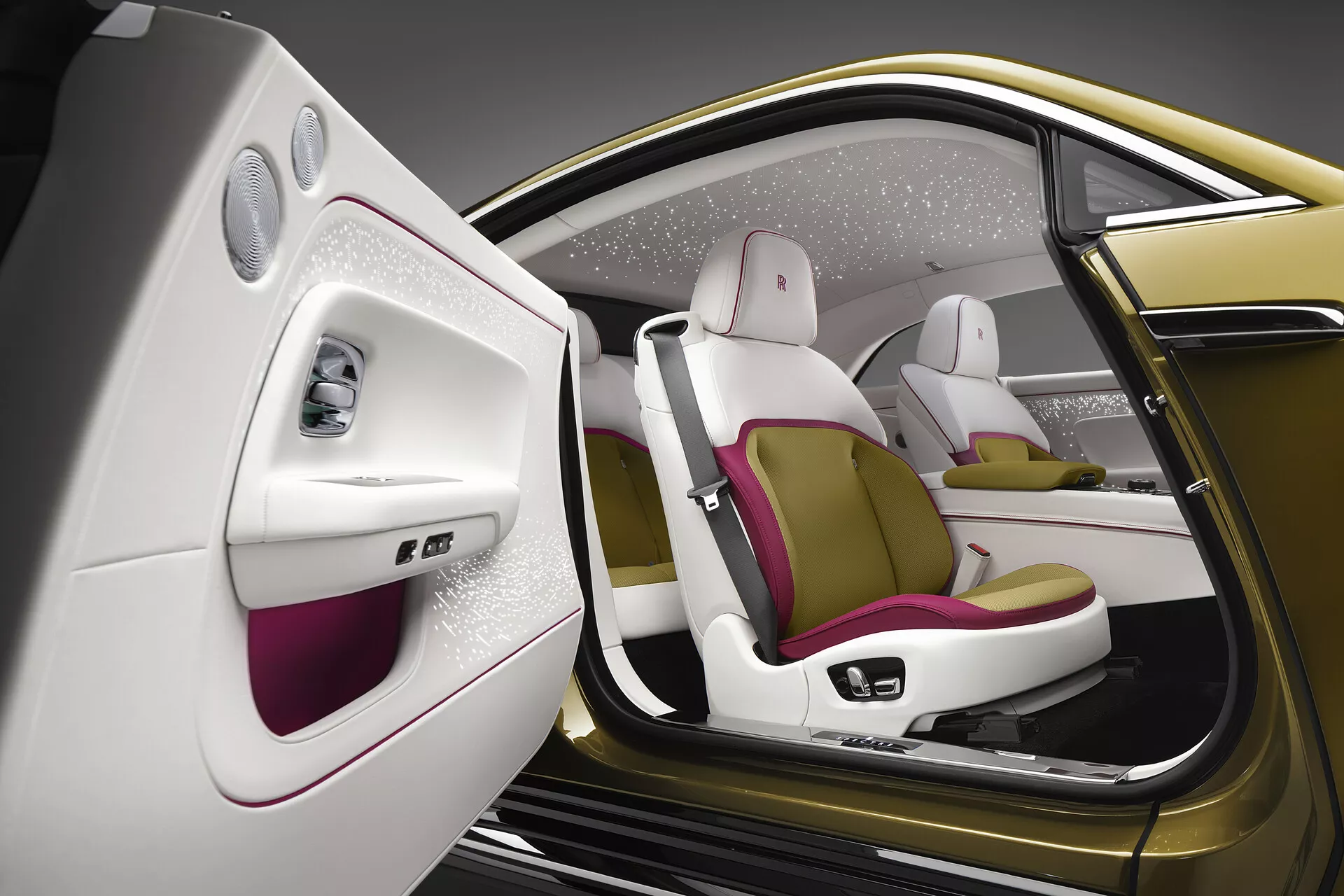 Visão detalhada do interior do Rolls-Royce Spectre 2023, mostrando seu lado passageiro de luxo com a porta aberta, destacando o design minimalista da porta, assentos ergonômicos em dois tons com acentos magenta e materiais de alta qualidade