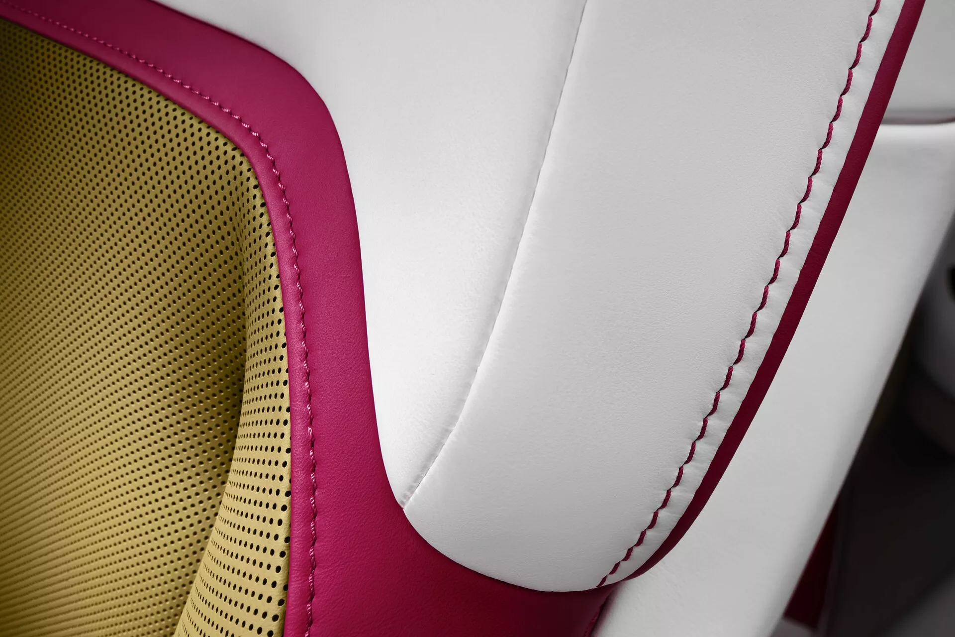 Close-up do assento do Rolls-Royce Spectre 2023 exibindo estofamento de couro de alta qualidade em dois tons, costura contrastante vermelha e padrão de colmeia para respirabilidade e conforto, incorporando luxo e artesanato.