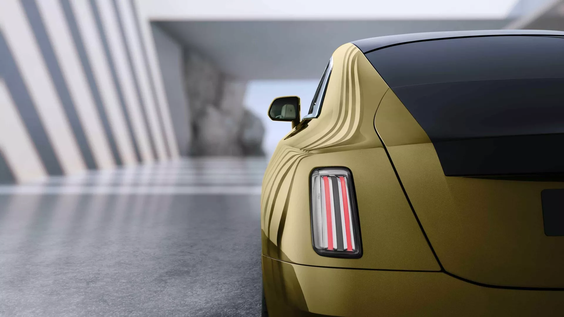 Rolls-Royce Spectre 2023, 1ª Geração, exibido com uma visão traseira em close, destacando o sofisticado design de luzes traseiras LED, acabamento em ouro metálico, e perfil coupé esportivo em um ambiente de showroom