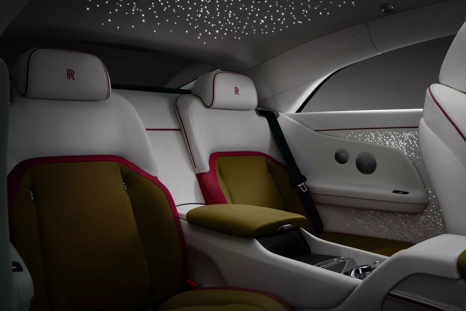 Interior luxuoso do Rolls-Royce Spectre primeira geração 2023 com assentos traseiros ergonômicos em couro com detalhes brancos e vermelho escuro, console central avançado, revestimento do teto tipo céu estrelado e iluminação ambiente de alta qualidade