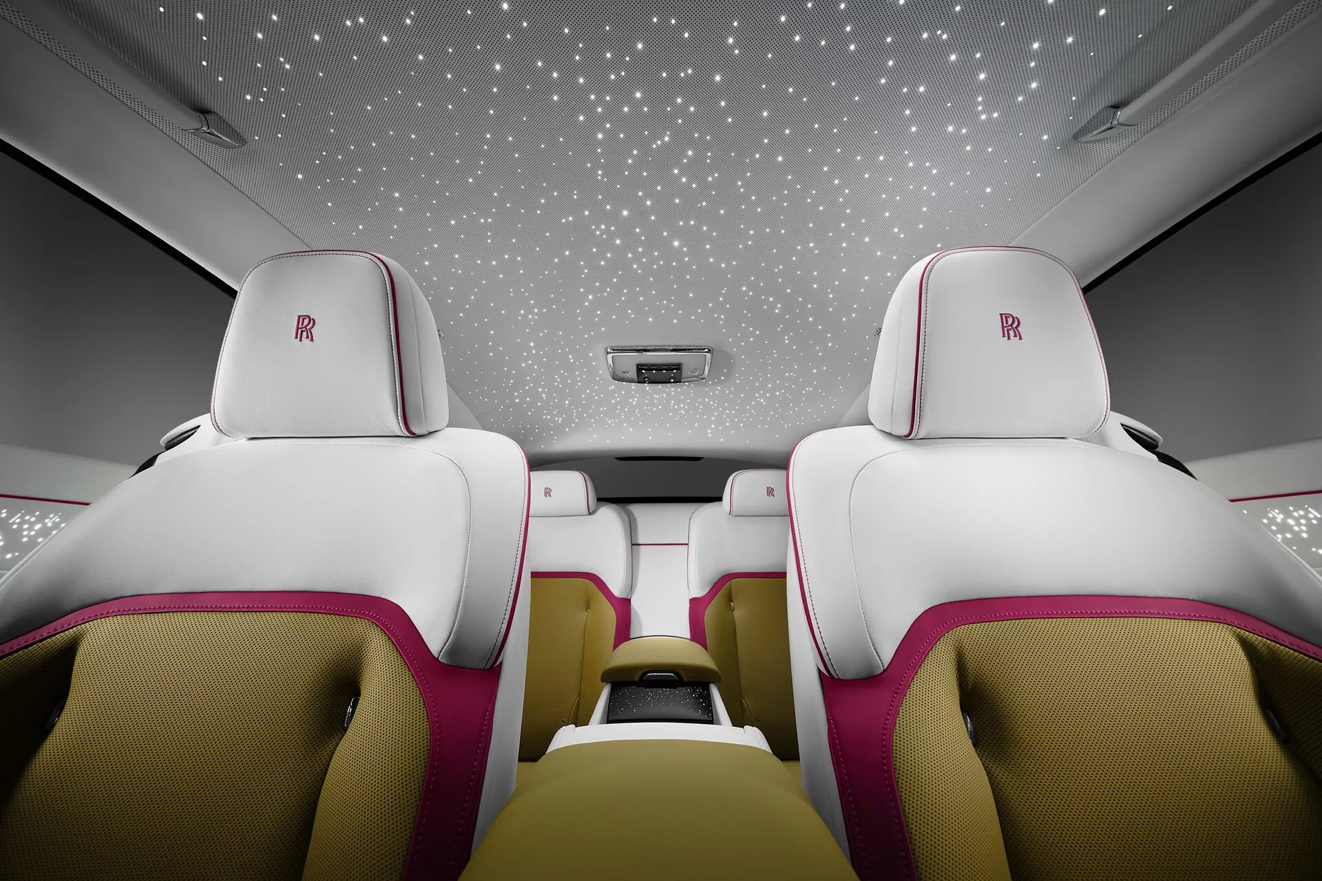 Interior do Rolls-Royce Spectre 2023 exibindo assentos luxuosos de couro branco e rosa, teto forrado a estrelas e recursos de cabine de alta qualidade a partir de uma vista voltada para trás