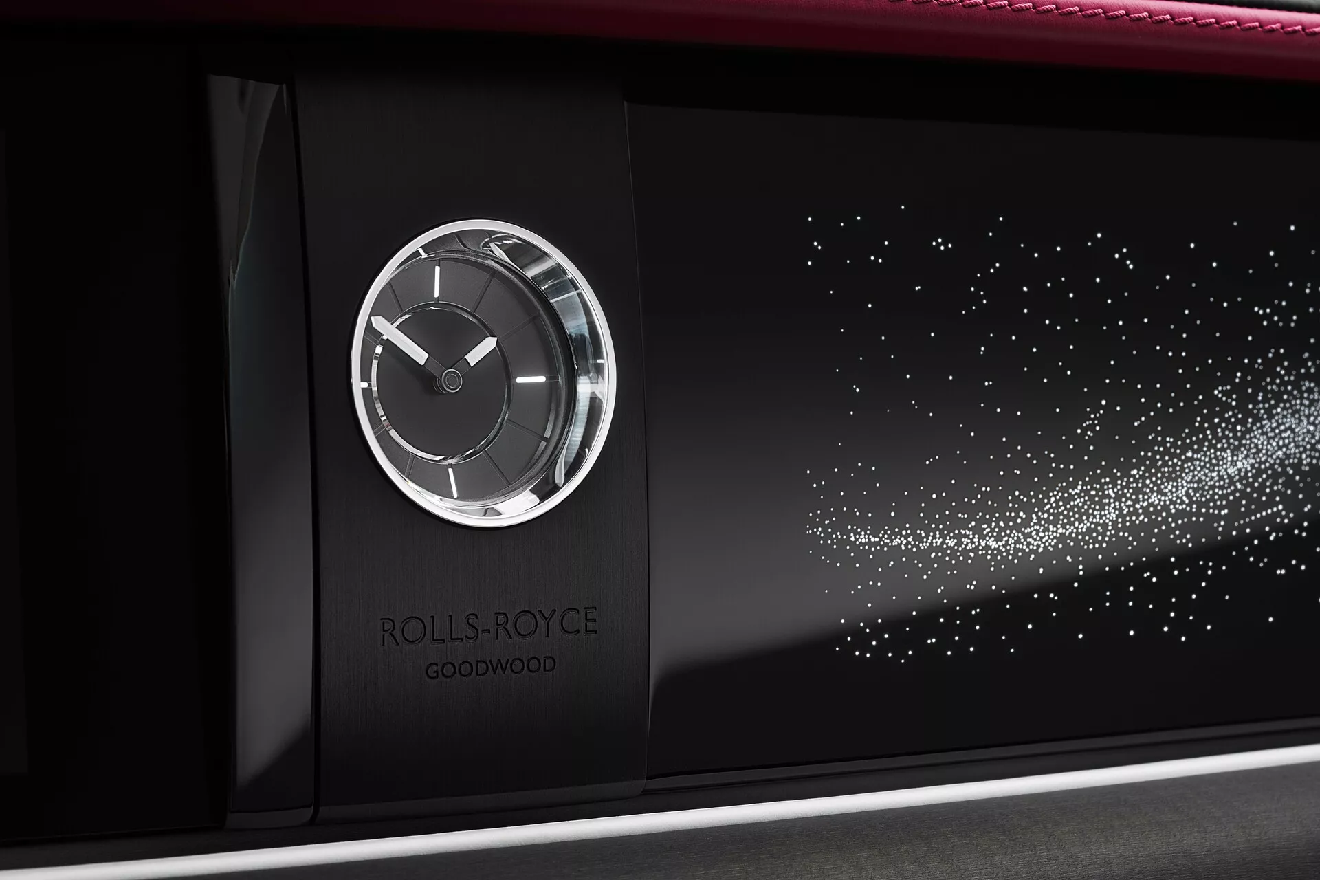 Detalhe do painel do Rolls-Royce Spectre 2023 mostrando um relógio analógico em uma caixa metálica com o logotipo no centro e uma característica de padrão de luz estelar contra um fundo preto brilhante, indicativo de personalização e design de luxo.
