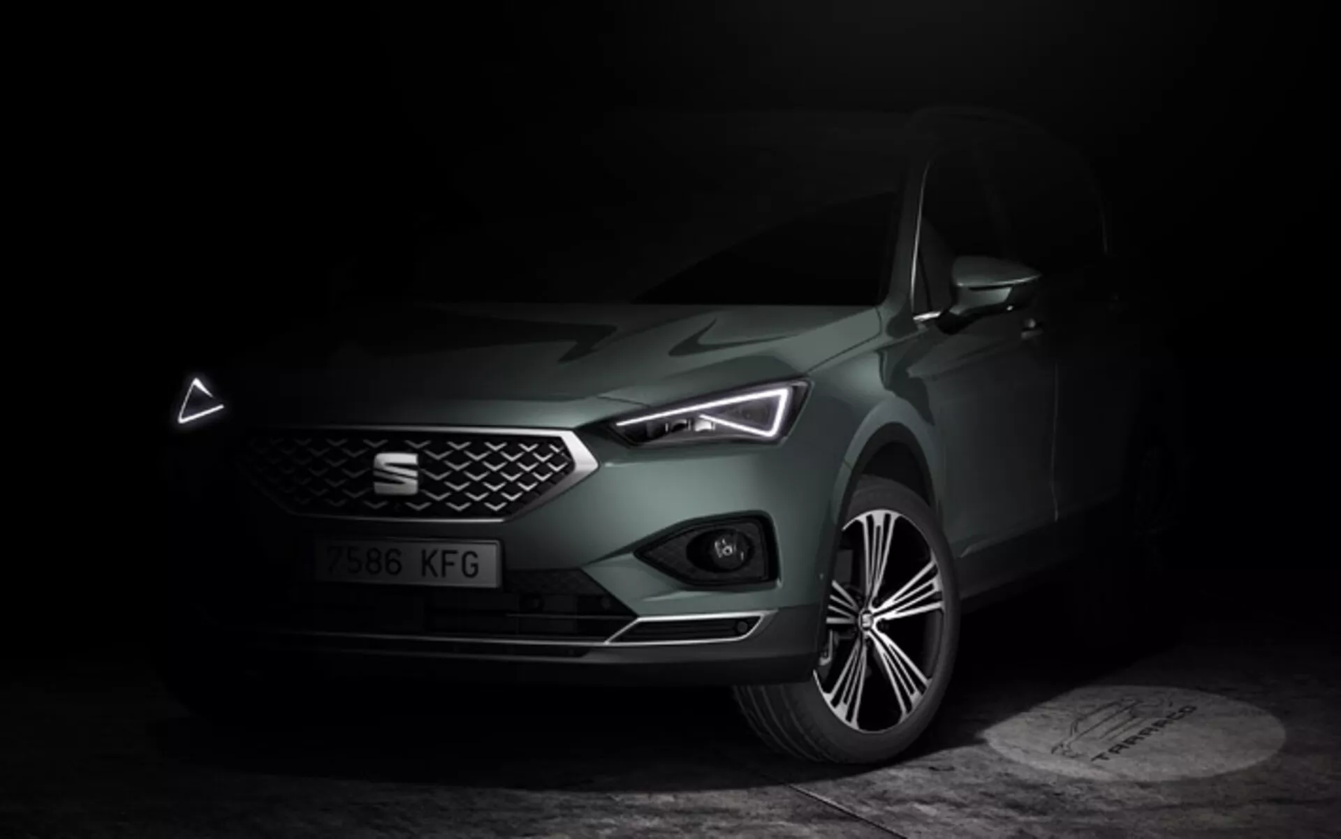 Seat Tarraco 2019 fotografado em iluminação suave, destacando suas características de design moderno a partir do ângulo frontal lateral, ressaltando os faróis LED, grade proeminente com emblema, para-choque dianteiro com entradas de ar visíveis e design de roda de liga leve de múltiplos raios.
