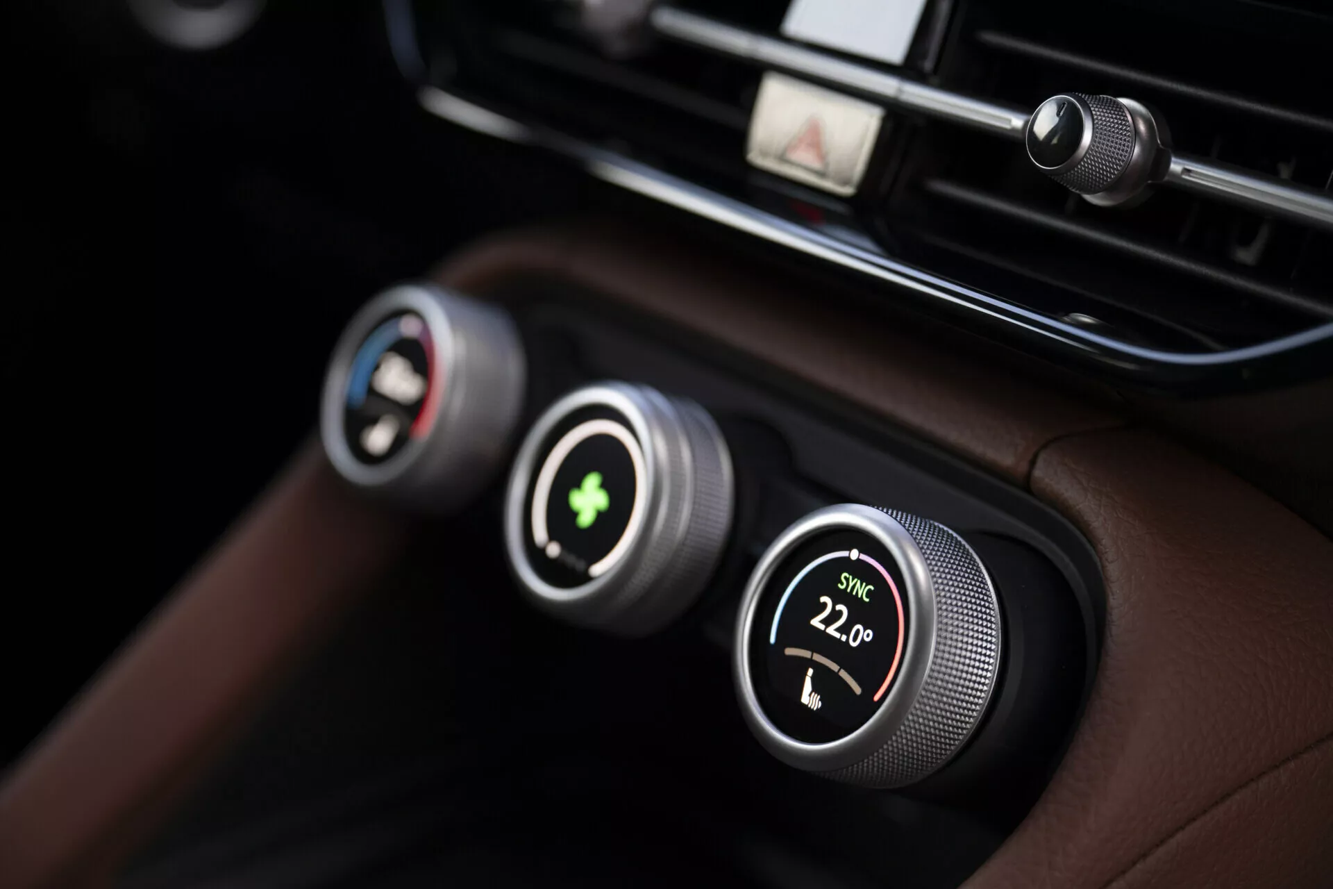 Vista de perto do sistema de controle climático da Skoda Kodiaq 2024 com controles de temperatura de zona dupla com botões metálicos e displays digitais, definido contra um painel de luxo de couro preto