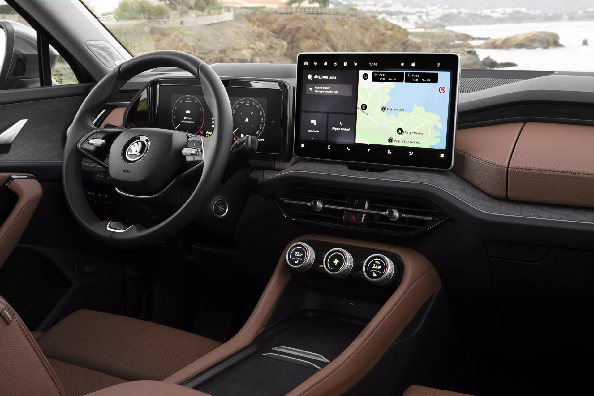Close-up do interior do Skoda Kodiaq 2024 mostrando o painel e as características tecnológicas a partir da perspectiva do motorista, incluindo um cluster de instrumentos digital, sistema de infotainment com tela sensível ao toque e navegação, estofamento de luxo em dois tons, iluminação ambiente e opções de conectividade modernas