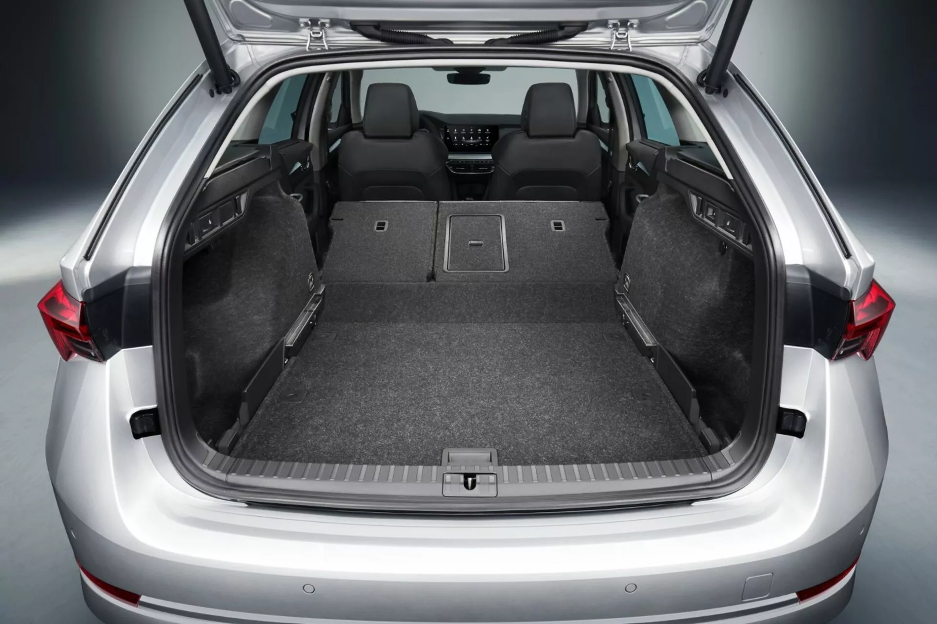 Porta-malas aberto do hatchback Skoda Octavia 2017 mostrando amplo espaço de carga com assentos traseiros rebatidos, piso plano, revestimento de carpete, pontos de ancoragem para armazenamento seguro e possíveis recursos tecnológicos avançados como luzes LED
