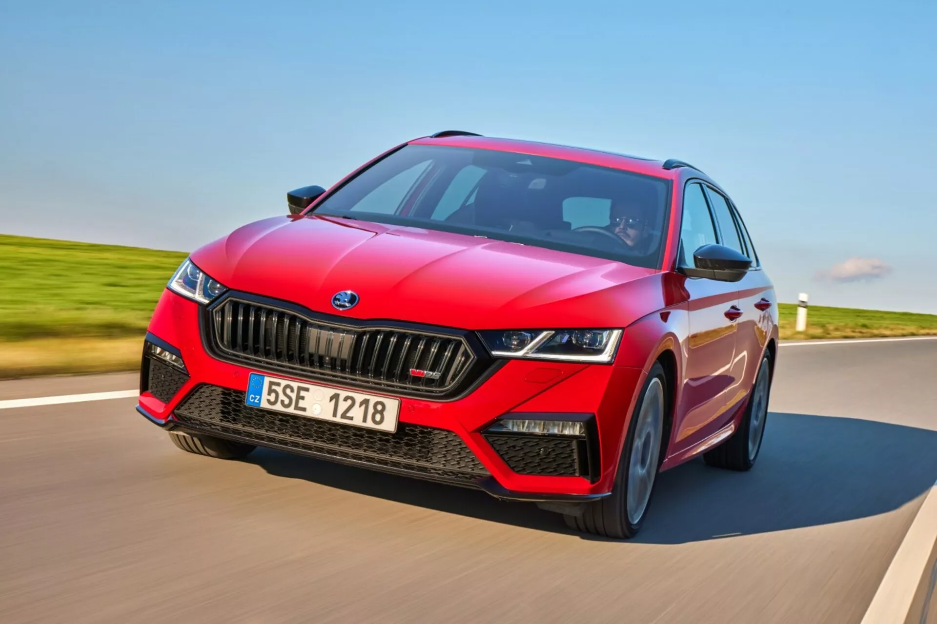 Skoda Octavia RS hatchback 2017 em movimento dinâmico em uma estrada pavimentada, exibindo design esportivo vermelho com acentos pretos, faróis LED e recursos tecnológicos avançados, incluindo ADAS e teto solar panorâmico