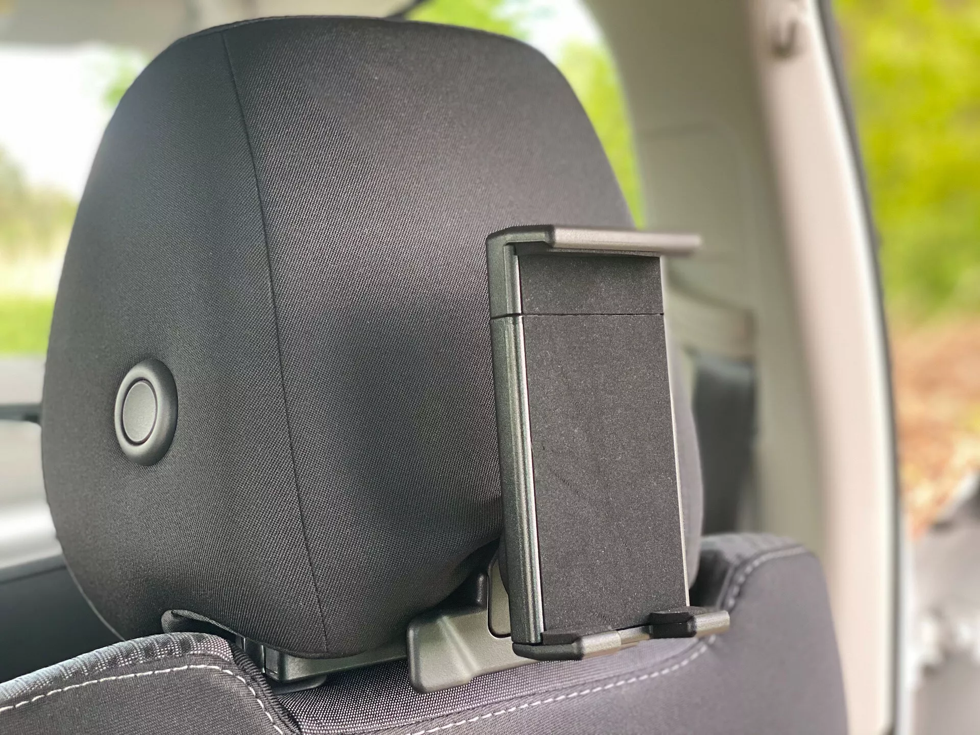 Visão aproximada do apoio de cabeça de um Škoda Octavia 2020 (Octavia-Limousine) a partir de um ângulo lateral interno, destacando o mecanismo de ajuste do apoio de cabeça e o acessório pendurador de casacos. O apoio de cabeça apresenta revestimento em tecido ou couro com um padrão sutil, focado no conforto e no design.