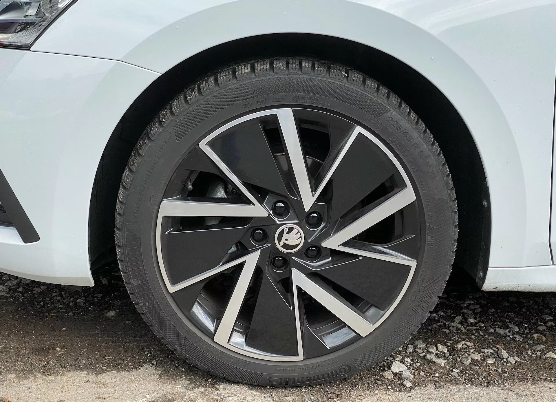 Close-up da roda dianteira de uma limusine Skoda Octavia 2020, mostrando uma roda de liga leve de cinco raios moderna com acabamento em dois tons e faces usinadas nos raios, capturada em um ângulo de 45 graus destacando seu design dinâmico semelhante a uma turbina e o padrão de trepidação visível de um pneu para todas as estações.