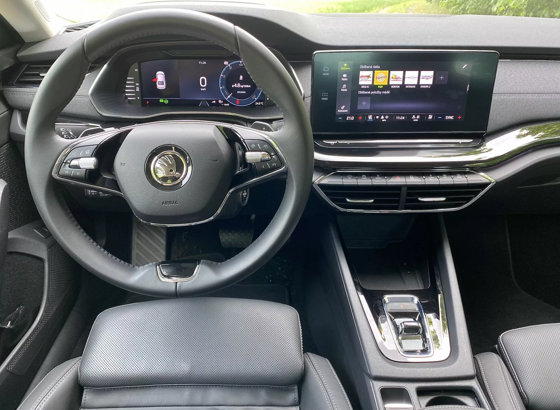 Interior de um moderno Skoda Octavia Limousine 2020, destacando a perspectiva do condutor com um volante multifuncional de três raios, painel de instrumentos digital, ecrã tátil horizontal largo do sistema de infoentretenimento, saídas de ar elegantes e alavanca de mudanças automática. O interior de luxo apresenta assentos em couro e acentos metálicos.