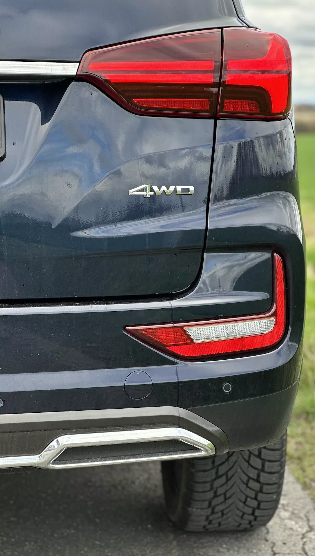 Vista detalhada do canto traseiro do SsangYong Rexton 2021 mostrando conjunto de luz traseira LED, distintivo 4WD, sensor de estacionamento, cobertura de escape integrada em pintura metálica
