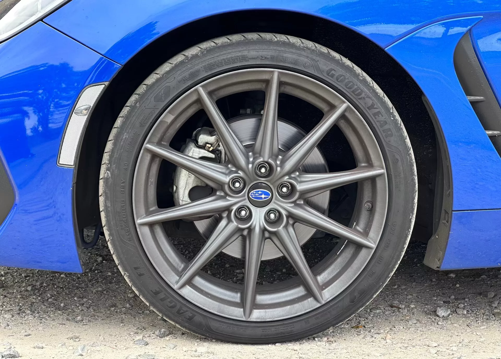 Imagem de close-up do Subaru BRZ 2023 mostrando a roda de liga frontal e o pneu Continental, com carroceria azul vibrante visível