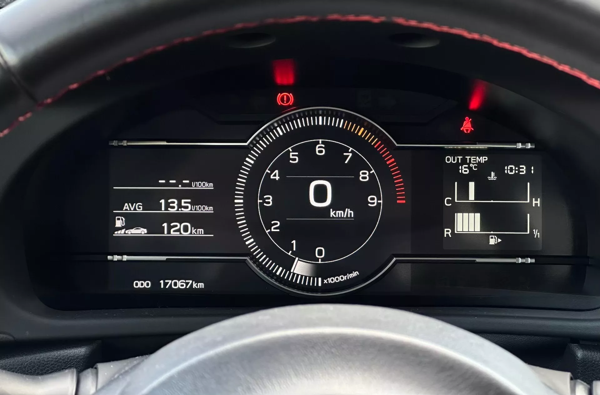 Vista detalhada do cluster de instrumentos do Subaru BRZ 2023 com foco no velocímetro e outros indicadores na perspectiva do motorista, apresentando volante com costura vermelha, combinação de indicações digitais-analógicas e indicadores tecnológicos como eficiência de combustível, temperatura e leituras do odômetro.