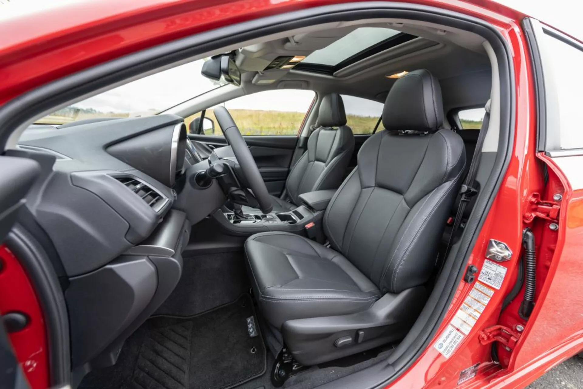 Vista interior do Subaru Impreza 2018 com foco no assento do passageiro frontal em couro preto e painel com sistema de infotenimento a partir de um ângulo oblíquo