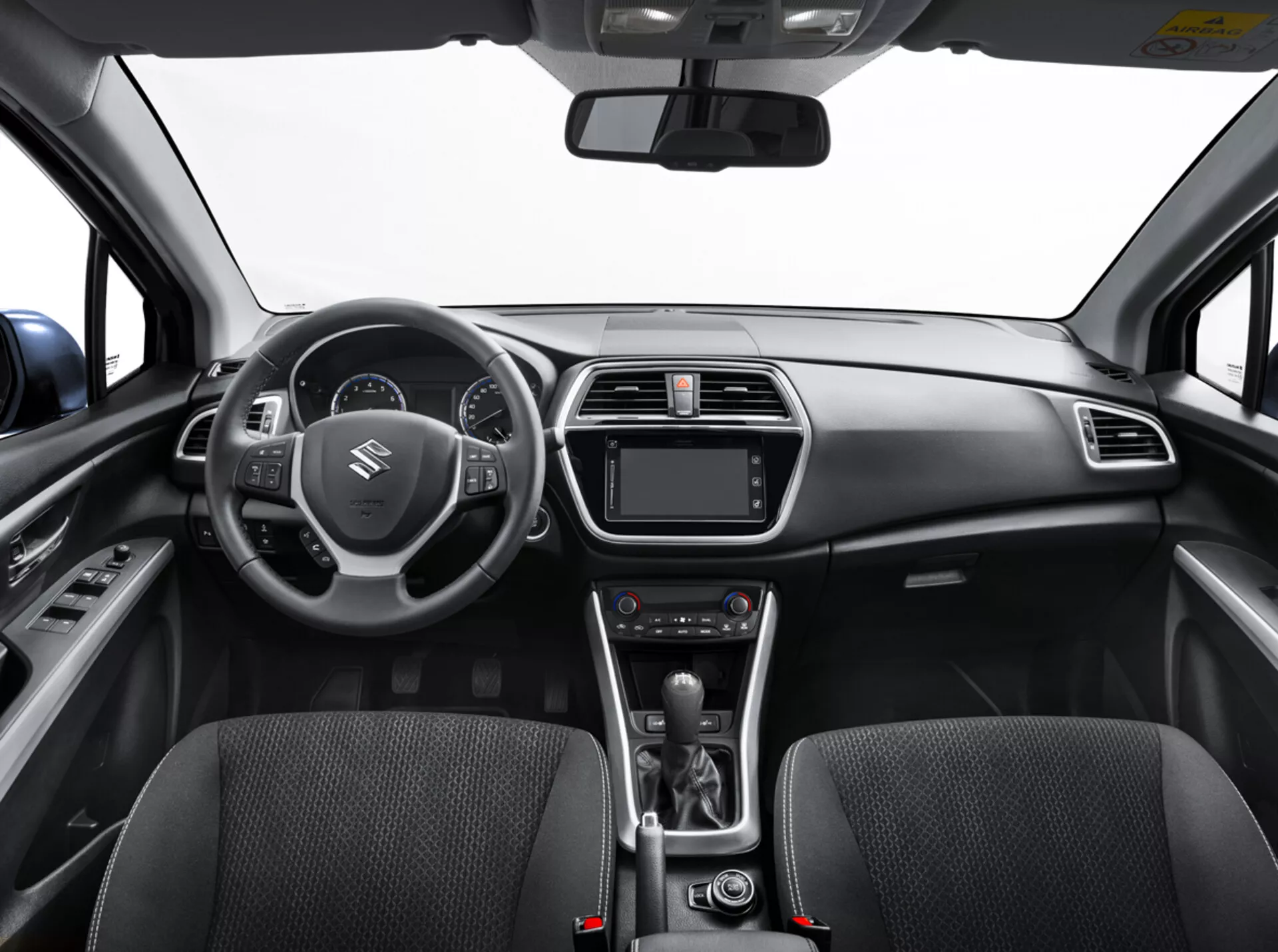 Vista interior do Suzuki S-Cross 2022 do banco traseiro mostrando o painel de instrumentos, volante com controles, cluster de instrumentos digital, sistema de infotainment, controles de clima, alavanca de câmbio automático e assentos dianteiros detalhados com textura de tecido