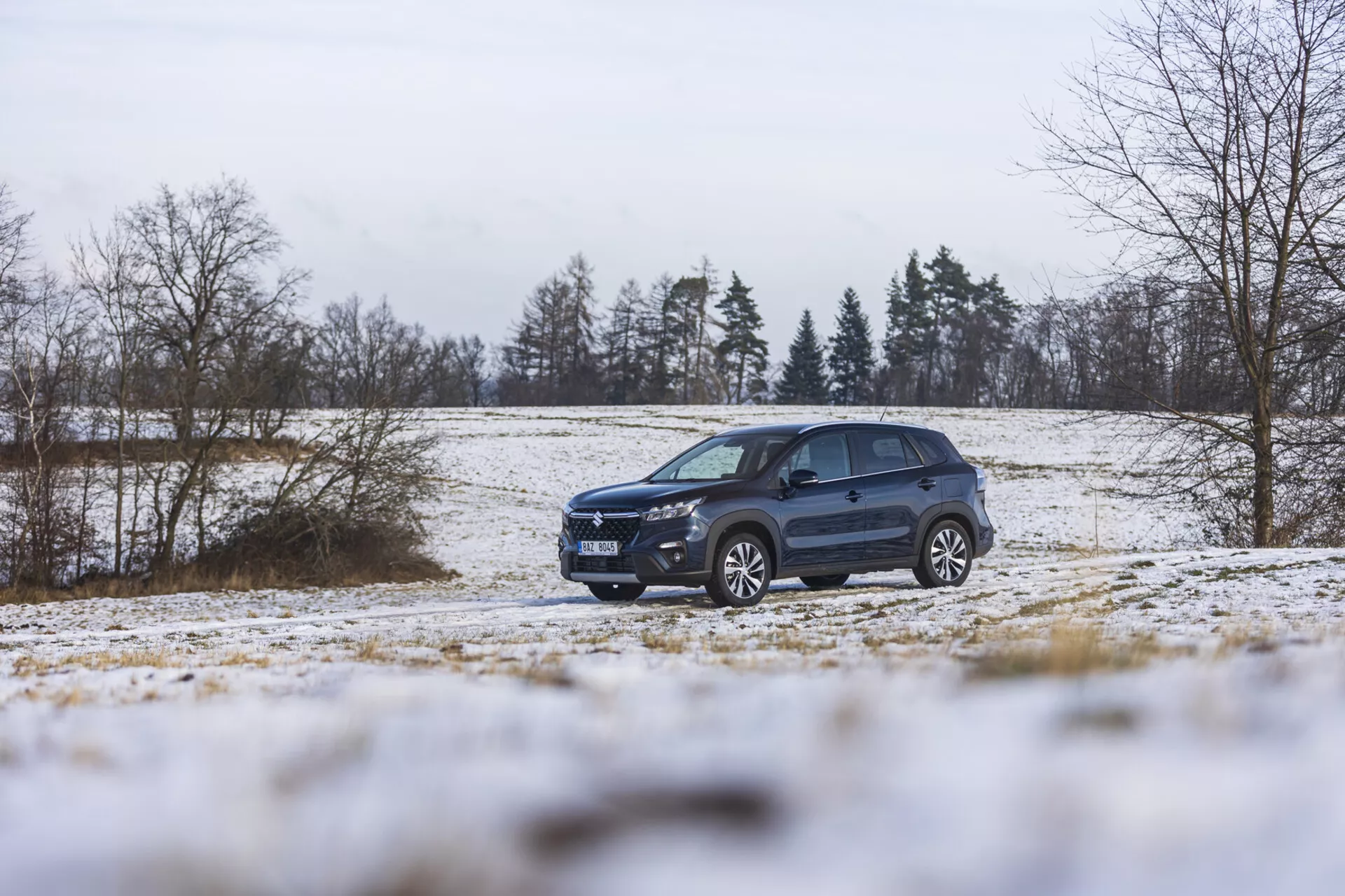 Suzuki S-Cross 2022 em uma paisagem de inverno com neve, exibindo seu design dinâmico, iluminação avançada, rodas de liga leve e racks de teto, enfatizando seu estilo de SUV e capacidade off-road.