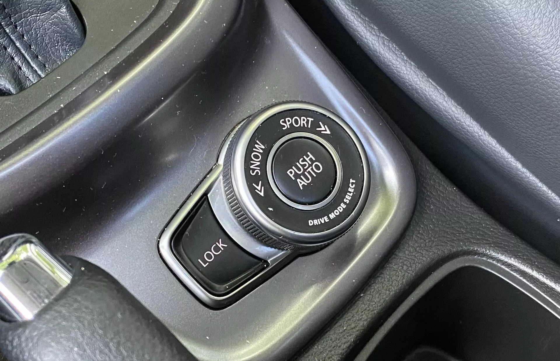 Close-up do seletor de modos de condução na consola central de um Suzuki Vitara 2018 com rótulos para os modos SNOW, SPORT, LOCK e AUTO, circunferência texturizada e detalhes metálicos escovados.