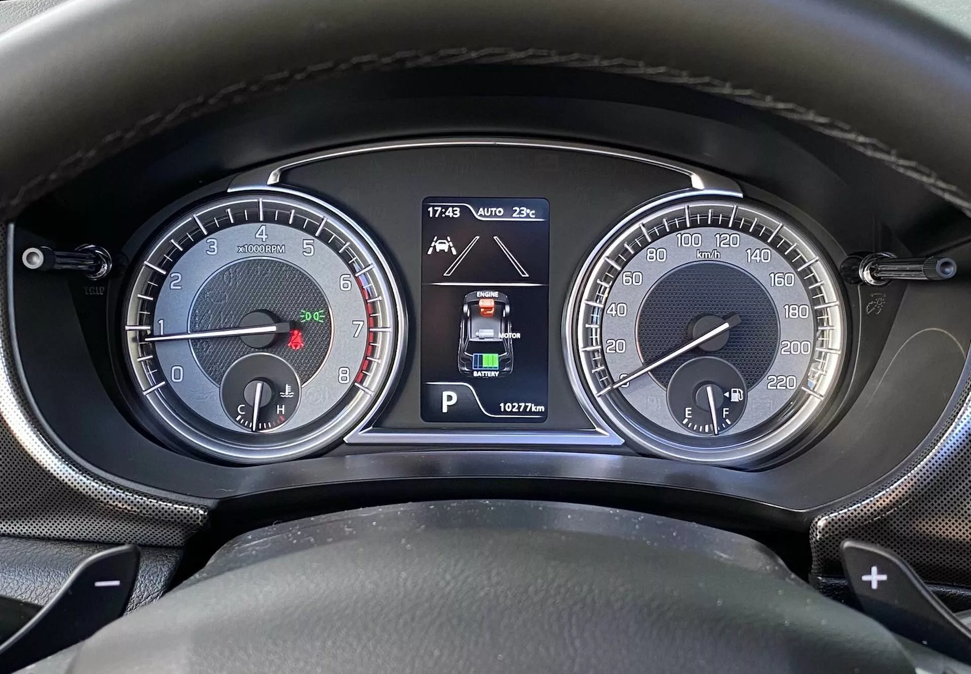 Close-up do painel de instrumentos/console do Suzuki Vitara 2018 a partir da perspectiva do motorista. A imagem apresenta dois mostradores analógicos, incluindo um tacômetro (até 7000 rpm) com um pequeno indicador de combustível e um velocímetro (até 260 km/h) com um pequeno indicador de temperatura do motor. Um display digital central mostra o modo de estacionamento (Park), indicadores de assistência de estacionamento, temperatura ambiente (20°C), horário (17:43) e quilometragem (162776 km). As marcações nos paddles indicam uma transmissão automática ou semi-automática.