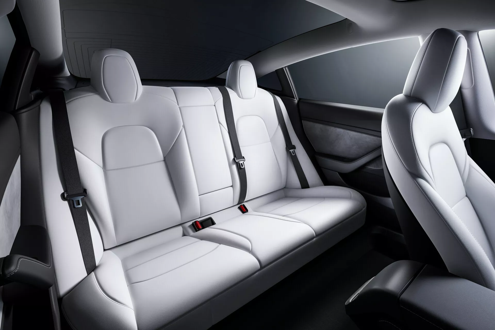 Interior do Tesla Model 3 2019 mostrando os assentos dianteiros e traseiros a partir de uma vista diagonal elevada, com assentos ergonômicos de couro ou couro sintético com encostos de cabeça ajustáveis, reforços laterais para conforto e segurança, design bicolor com detalhes elegantes e cintos de segurança visíveis, painéis das portas com alto-falantes integrados e unidades de controle elétrico.