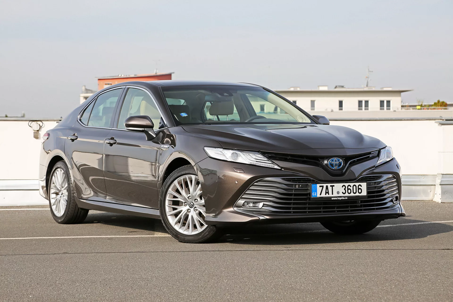 Imagem exterior do Toyota Camry Limousine 2019 exibindo a sofisticada grade dianteira grande, faróis LED angulares e elegantes, rodas de liga leve estilosas e recursos de segurança avançados sugerindo capacidades ADAS, capturados em um acabamento metálico brilhante.