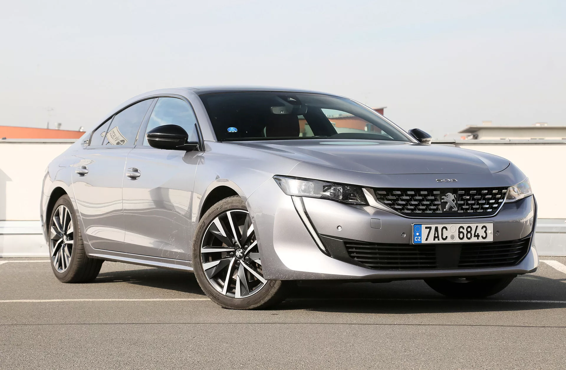 Toyota Camry Limousine 2019 mostrado em um ângulo frontal de três quartos destacando seus faróis LED elegantes, grade frontal distintiva com emblema central, capô projetado aerodinamicamente e perfil lateral com grandes rodas de liga leve multirraios, pintura brilhante e linha do teto estilo coupé