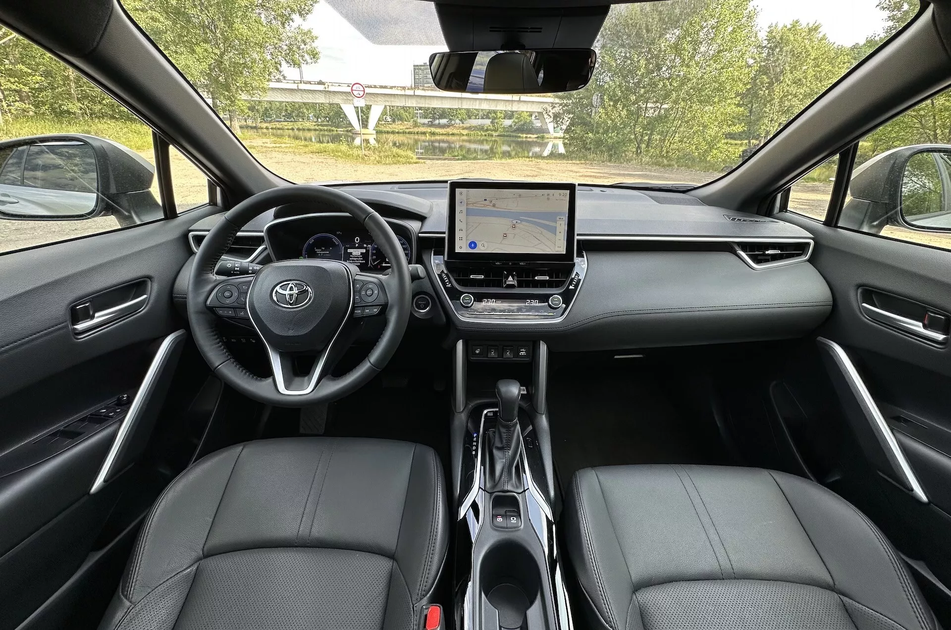 Vista interior do Toyota Corolla Cross 2022 do assento traseiro mostrando o painel de instrumentos, sistema de infotenimento com tela sensível ao toque e assentos dianteiros em couro