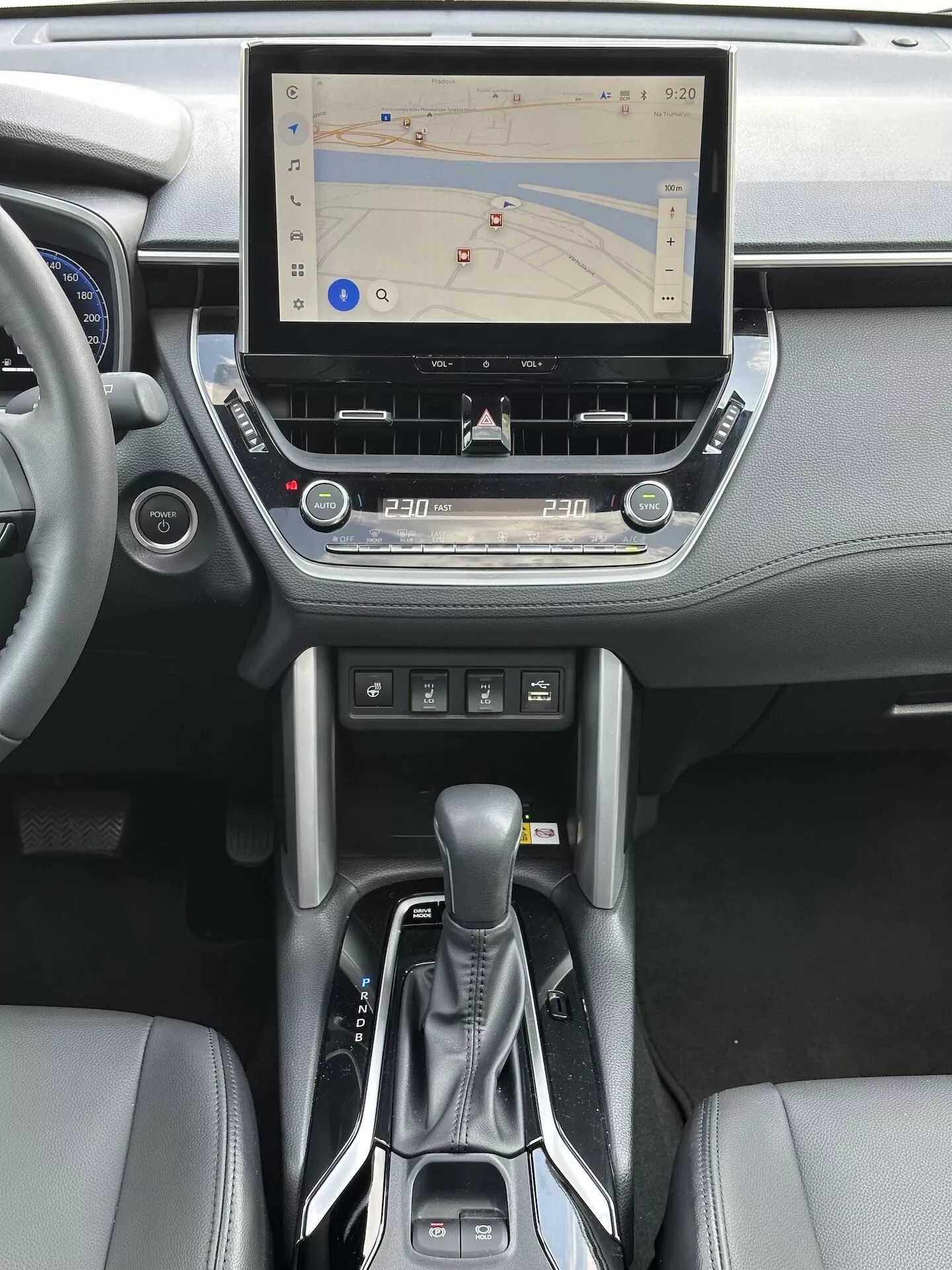 Interior do Toyota Corolla Cross 2022 com sistema de infotenimento tátil com navegação GPS, controle de clima de duas zonas, entrada para CD, botões de controle de mídia e telefone, alavanca de transmissão automática moderna e acabamentos em couro na consola central e design do painel de instrumentos