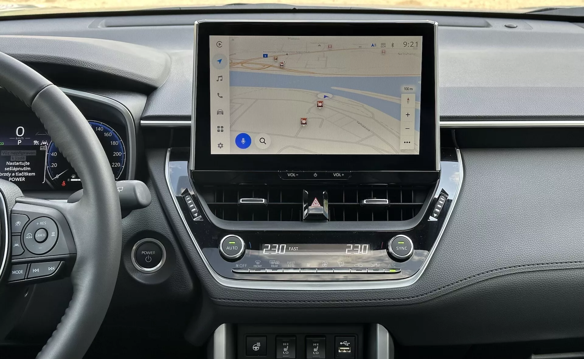 Interior do Toyota Corolla Cross 2022 mostrando um console central moderno com um grande display touchscreen vertical para navegação, cercado por elegantes elementos de painel de bordo incorporando detalhes em couro, cluster de instrumentos digitais ao lado do volante e controles táteis ergonômicos para clima e áudio, configurados em luz natural.