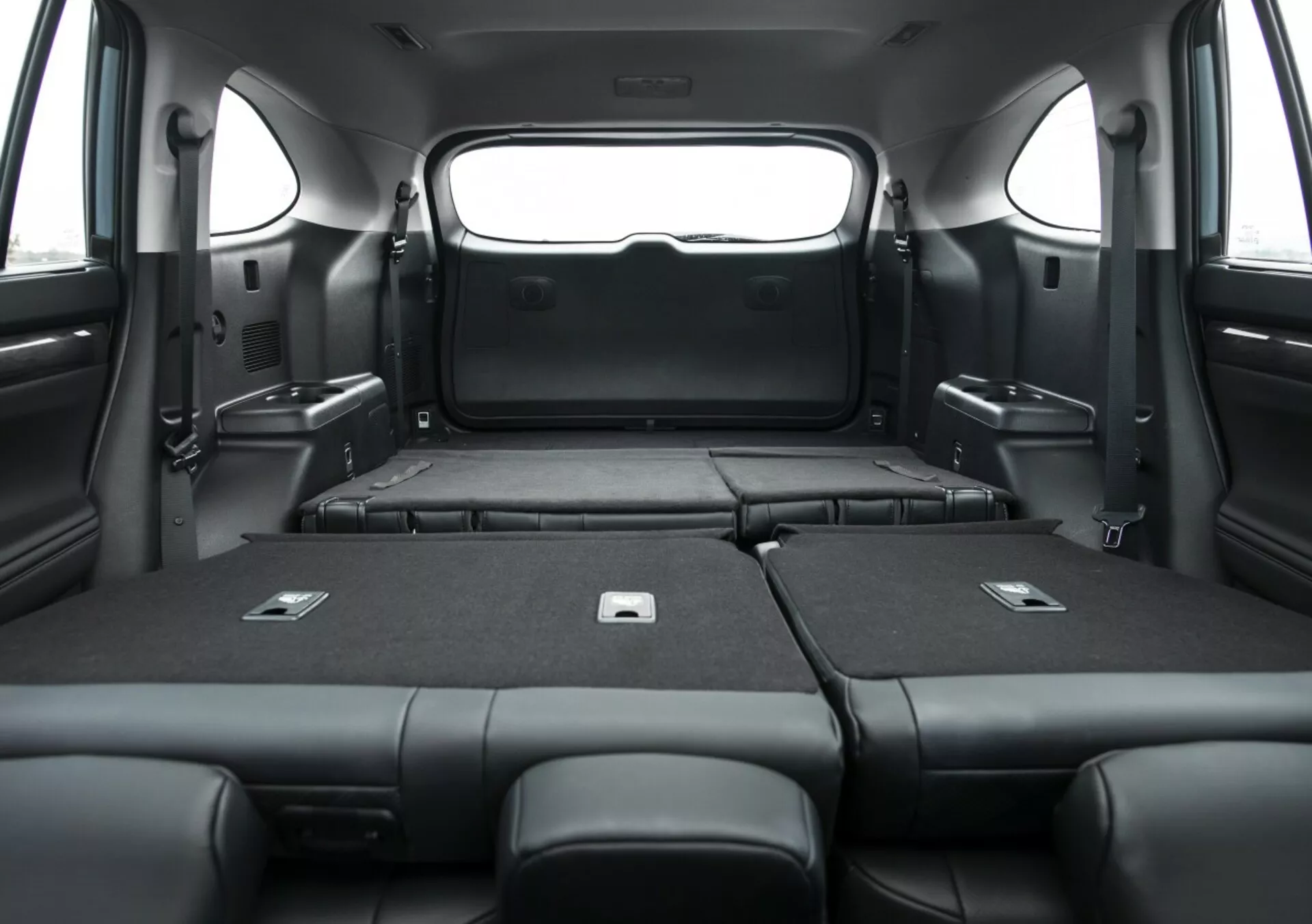 Vista interior do Toyota Highlander 2021, mostrando a área de carga expandida com os bancos traseiros rebatidos, destacando a capacidade espaçosa para bagagem e o elegante estofamento preto de uma perspectiva interna.