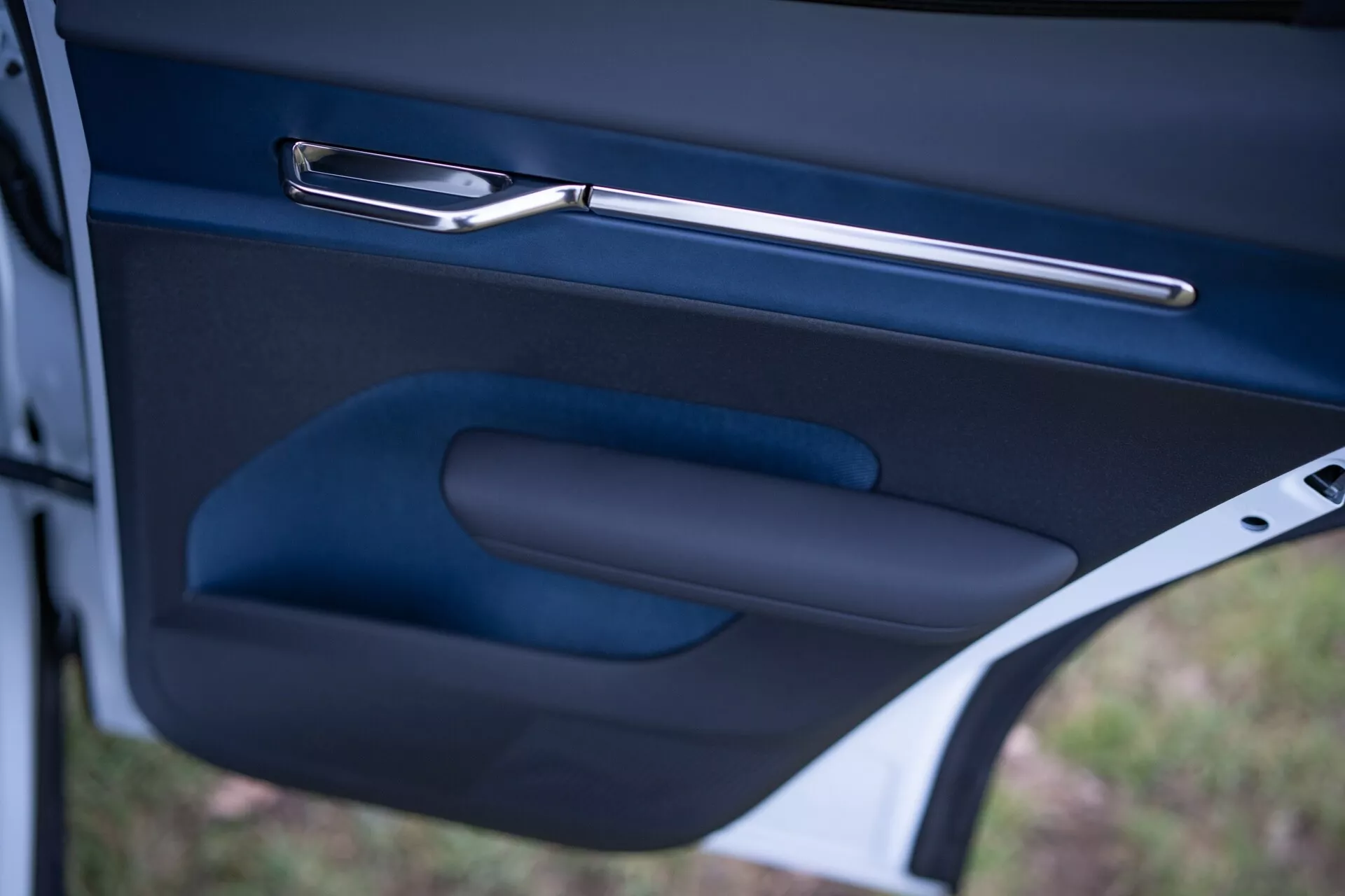 Close-up do interior da porta do Volvo EX30 2024, destacando a maçaneta da porta metálica elegante, apoio de braço ergonômico e bolso de armazenamento em um acabamento escuro de alta qualidade