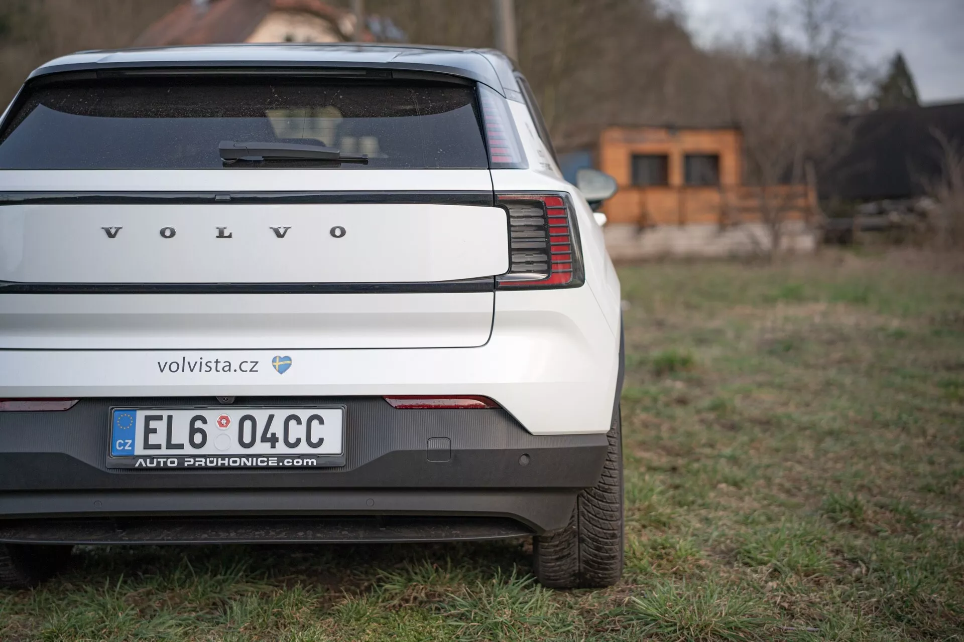 Vista traseira de um Volvo EX30 2024 destacando as luzes traseiras verticais únicas, para-choque traseiro e área da placa de licença em um fundo gramado