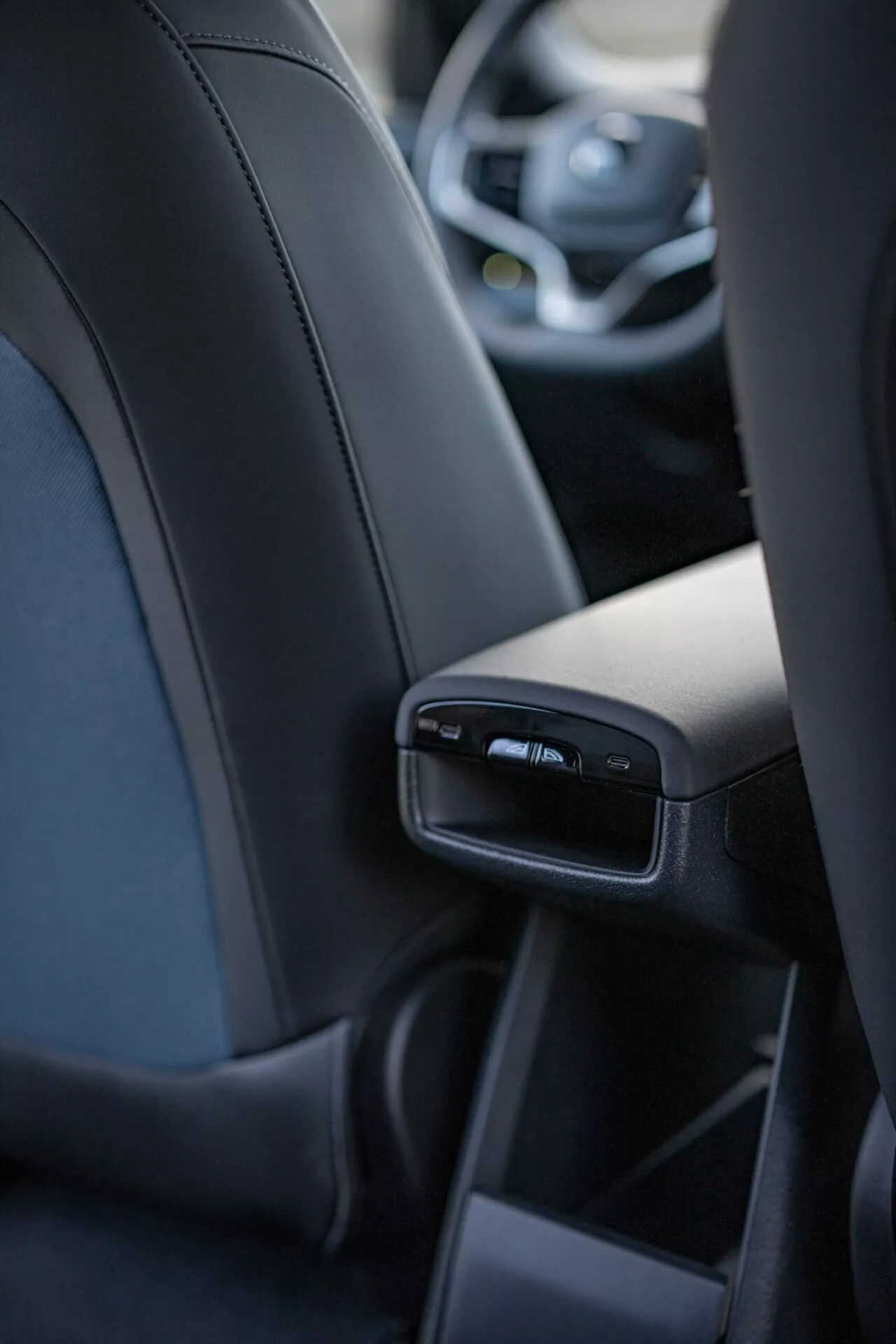 Vista interior do Volvo EX30 2024 focada nas características detalhadas do console central traseiro da perspectiva do passageiro central traseiro, incluindo portas USB e saídas de ar, exibindo luxo e tecnologia