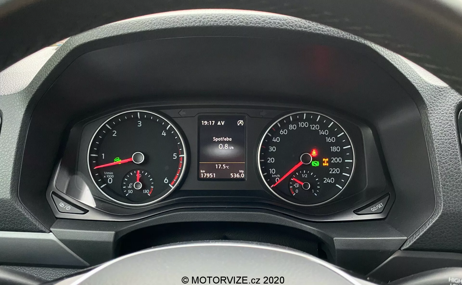 Vista detalhada do painel de instrumentos do motorista em um VW-Nutzfahrzeuge Amarok 2016 a partir do assento do motorista, mostrando o tacômetro e o velocímetro com displays digitais e analógicos, incluindo RPM do motor, velocidade, nível de combustível, temperatura do motor e dados do veículo, como velocidade atual, leitura do odômetro, temperatura externa e consumo de combustível.