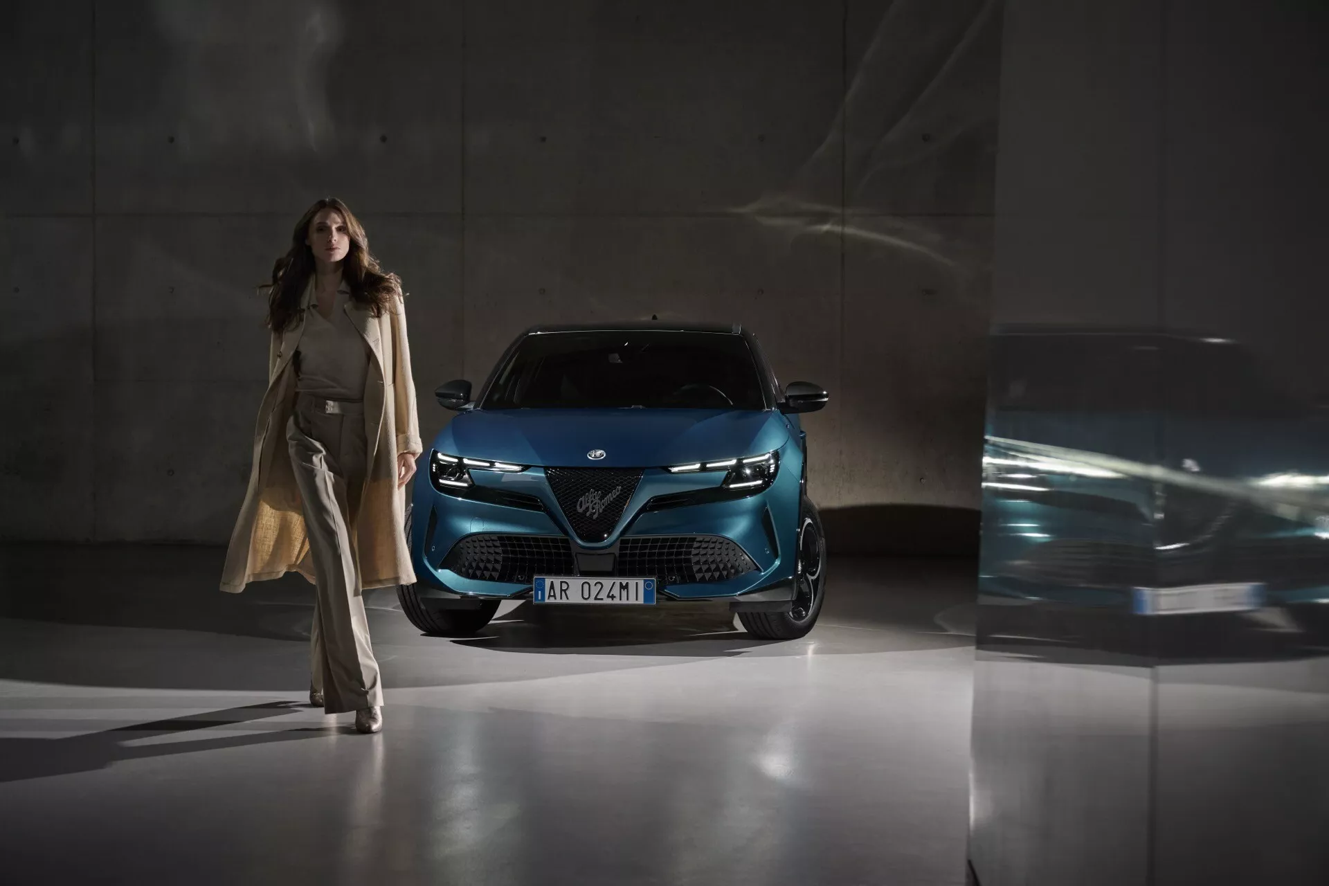 Alfa-Romeo Junior 2024 fotografado de um ângulo frontal baixo destacando a grade, faróis de LED e design frontal moderno em azul metálico profundo, destacando tecnologia avançada de iluminação e design em um ambiente urbano