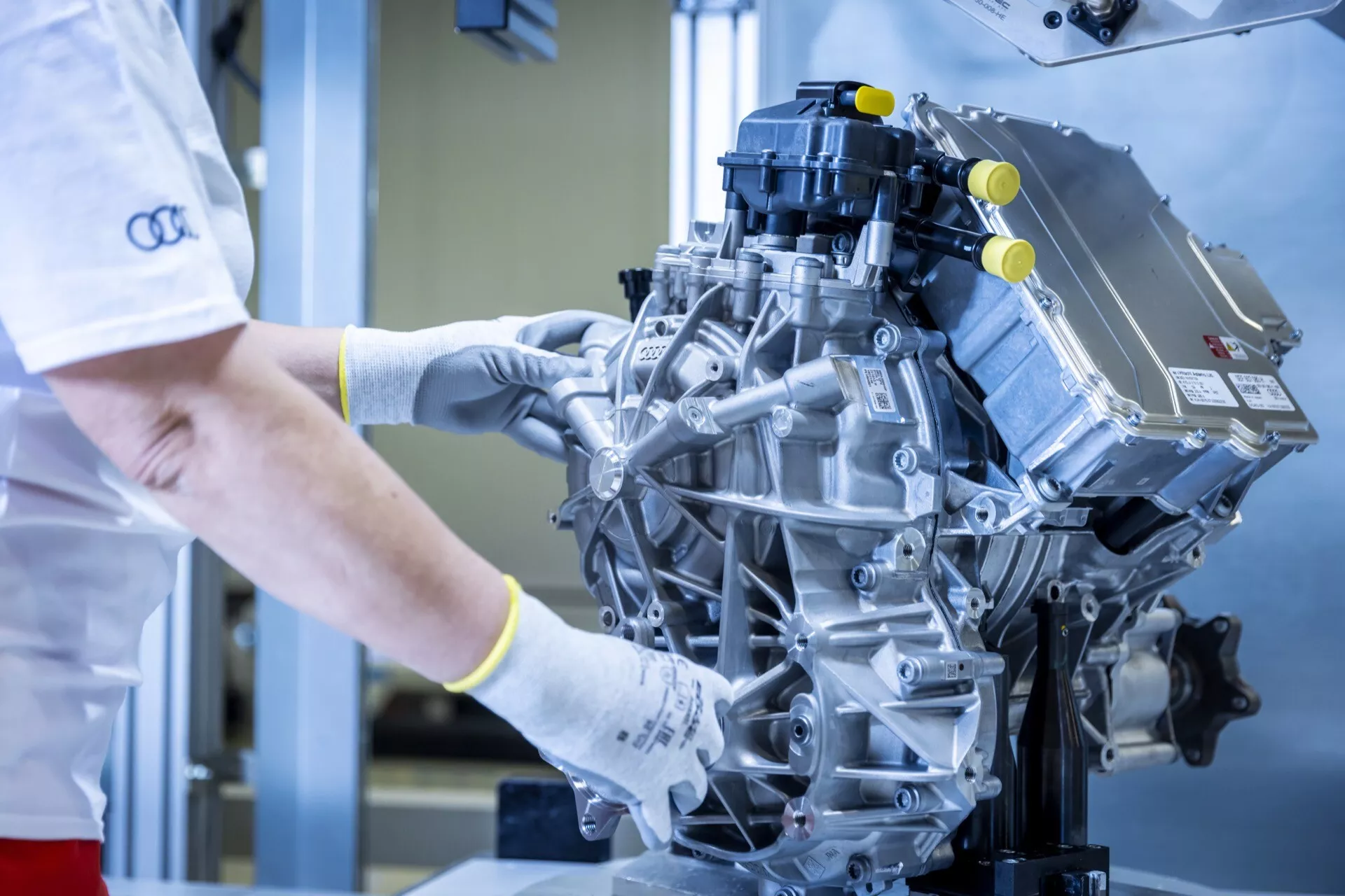 Visão detalhada de um motor moderno de alto desempenho com um técnico inspecionando-o em um ambiente industrial limpo, destacando componentes como o coletor de admissão e as bobinas de ignição.