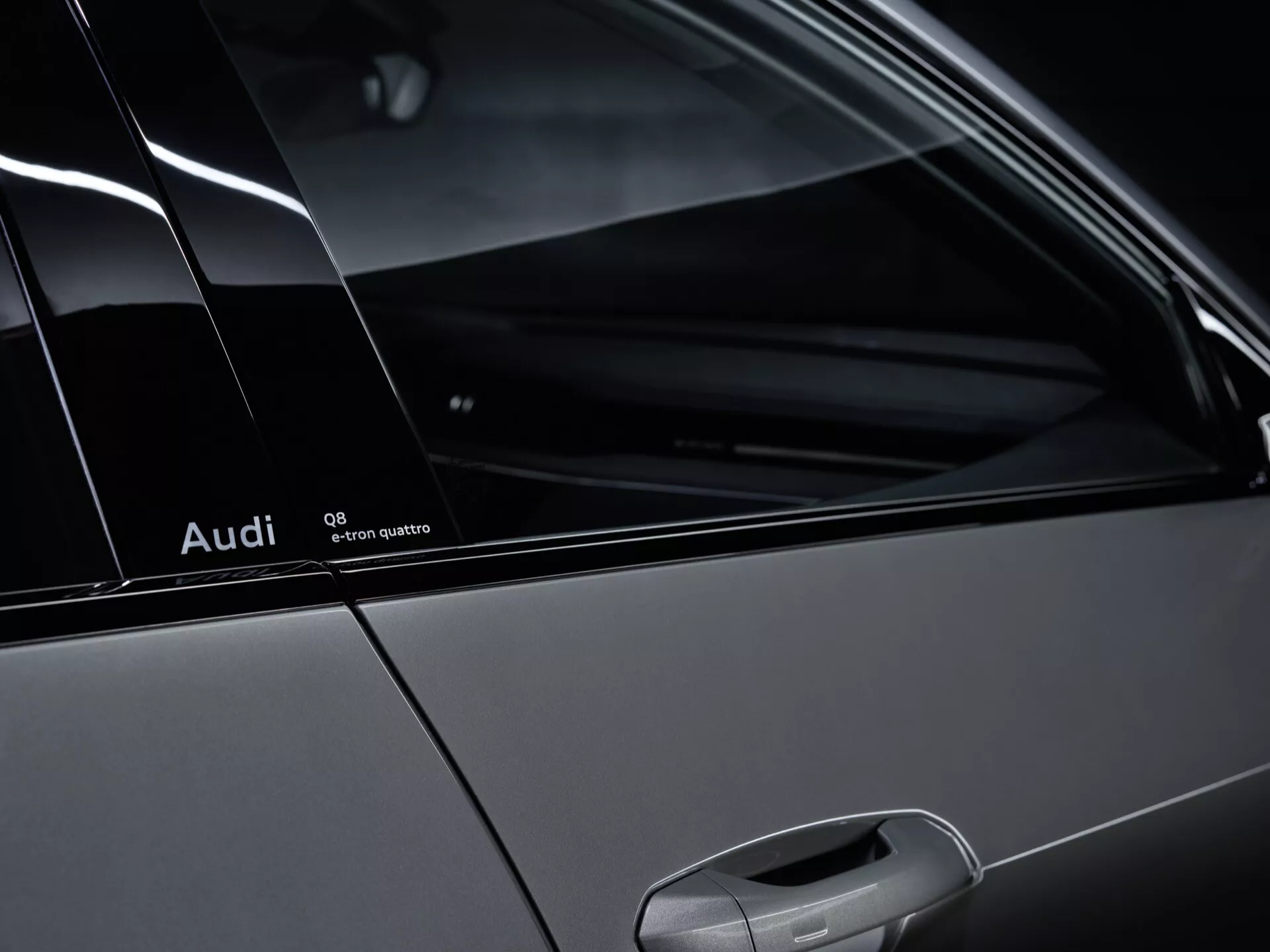 Detalhe do perfil lateral do Audi Q8-e-tron 2023 mostrando o emblema Quattro, o pilar C e a janela do passageiro traseiro, enfatizando o design do veículo e o sistema de tração nas quatro rodas